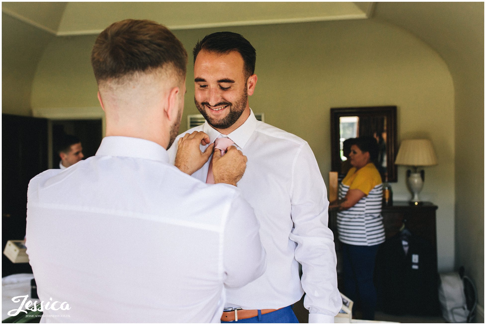 the best man helps the groom with his tie