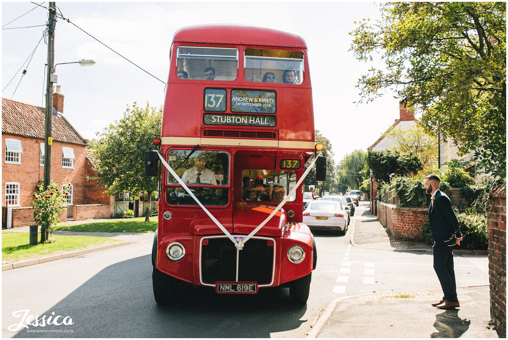 big red bus delivers the wedding guests at the church