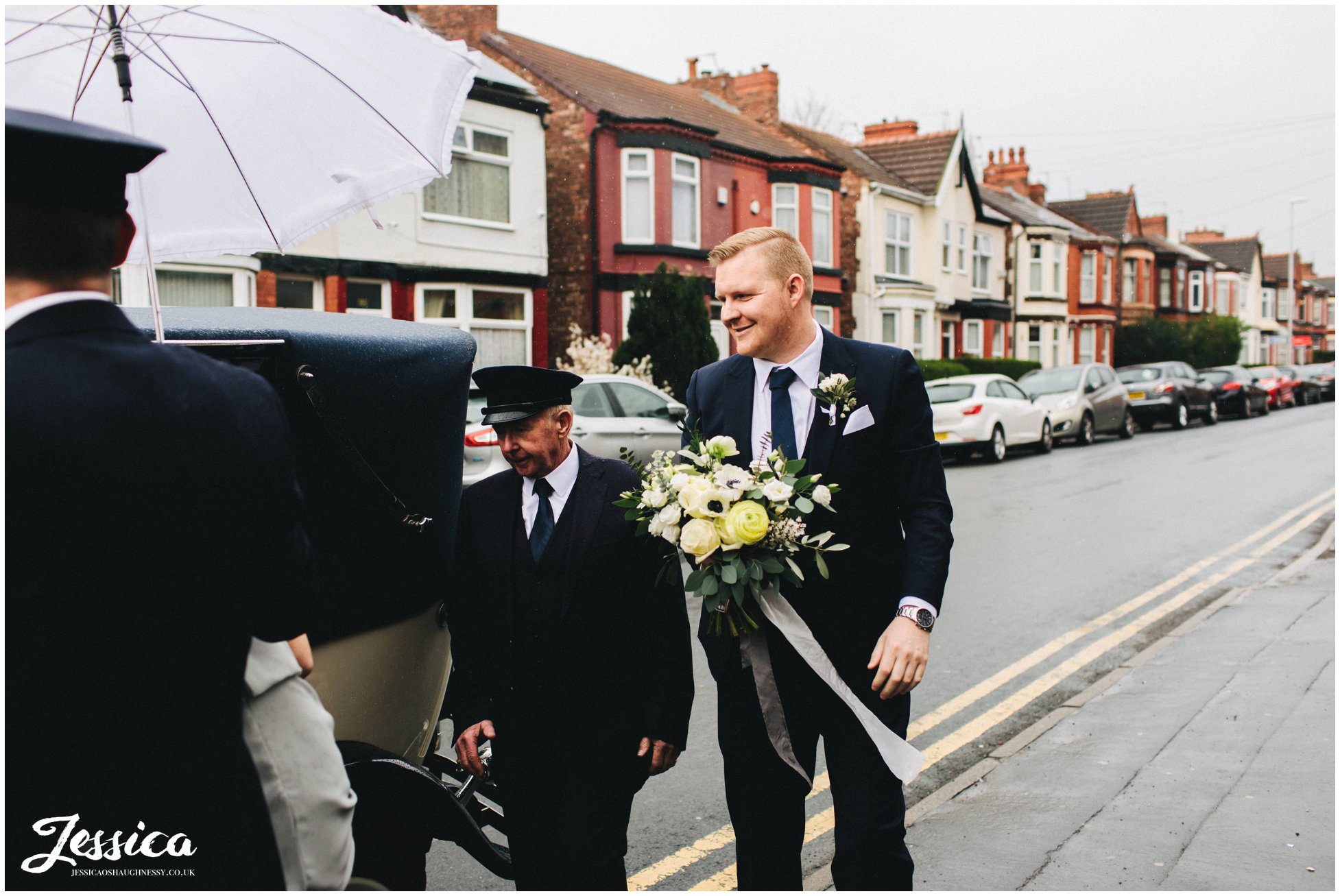 the brides brother holds her bouquet whilst she gets out the wedding car