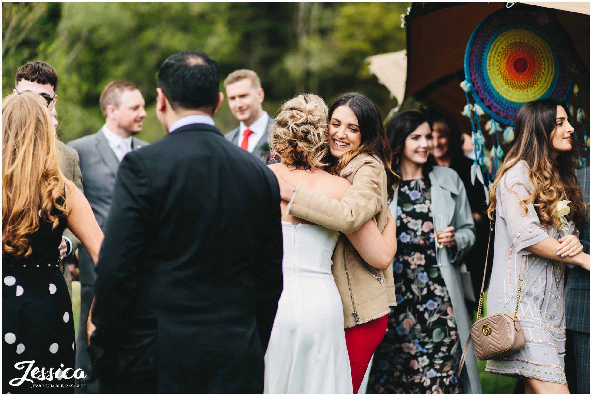 guests hugging as they arrive for the same sex tipi wedding