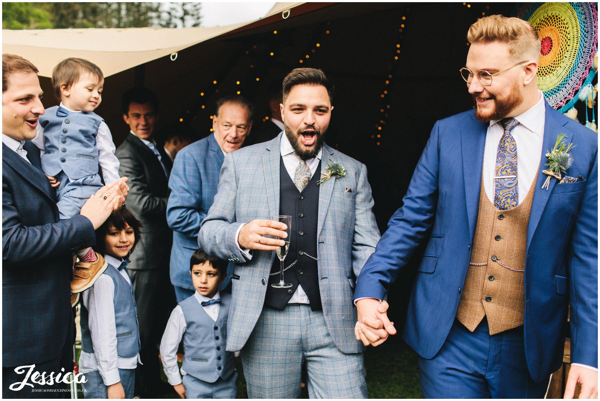 Grooms cheer as they walk down the aisle as a married couple