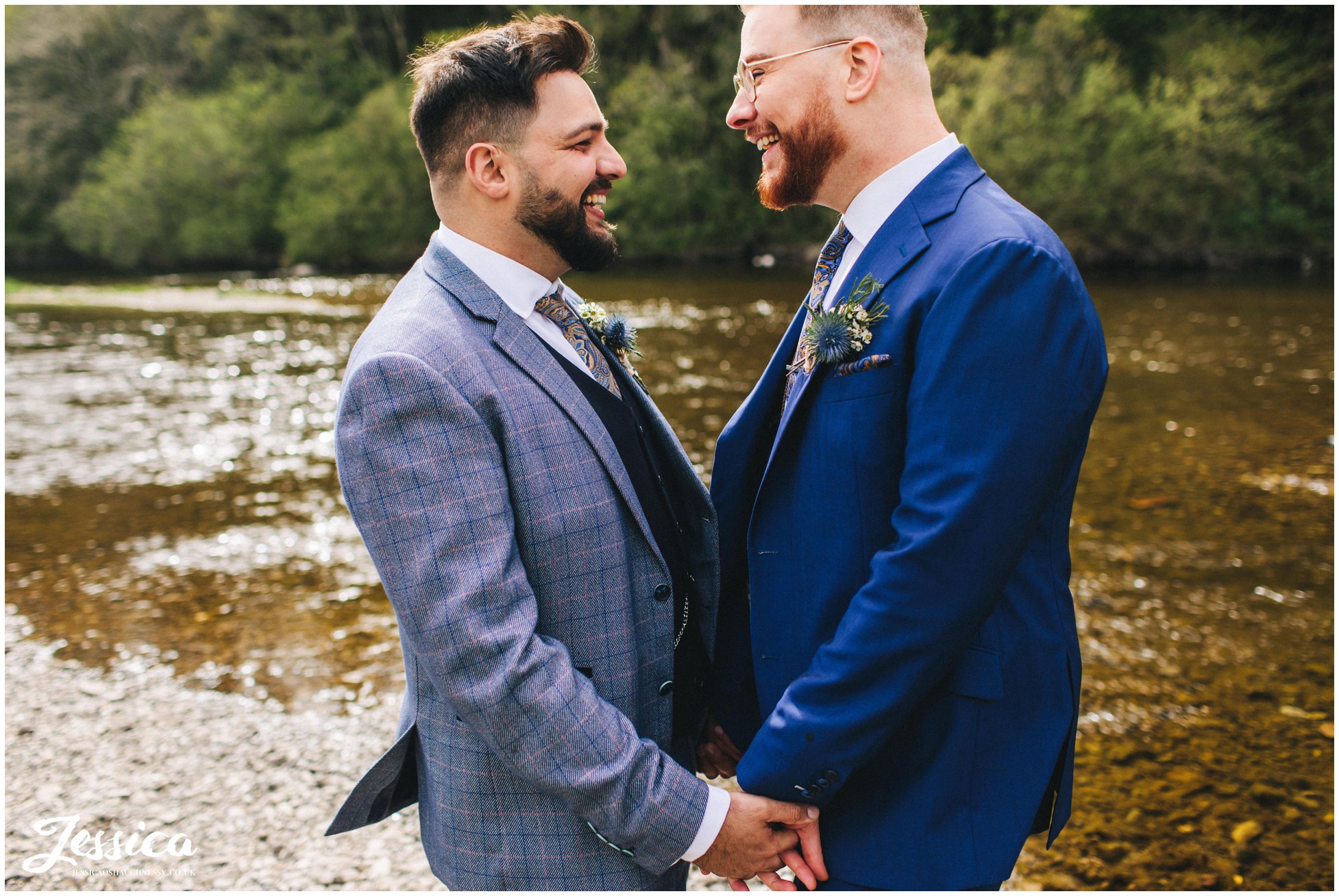 the grooms hold hands down by the river