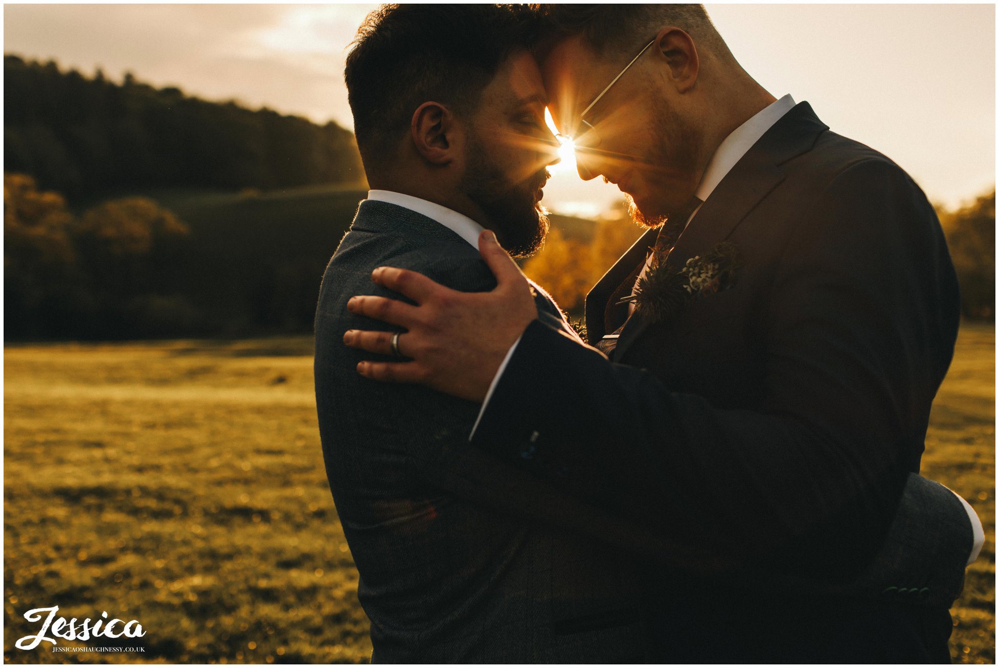 the grooms hold each other in the golden evening light