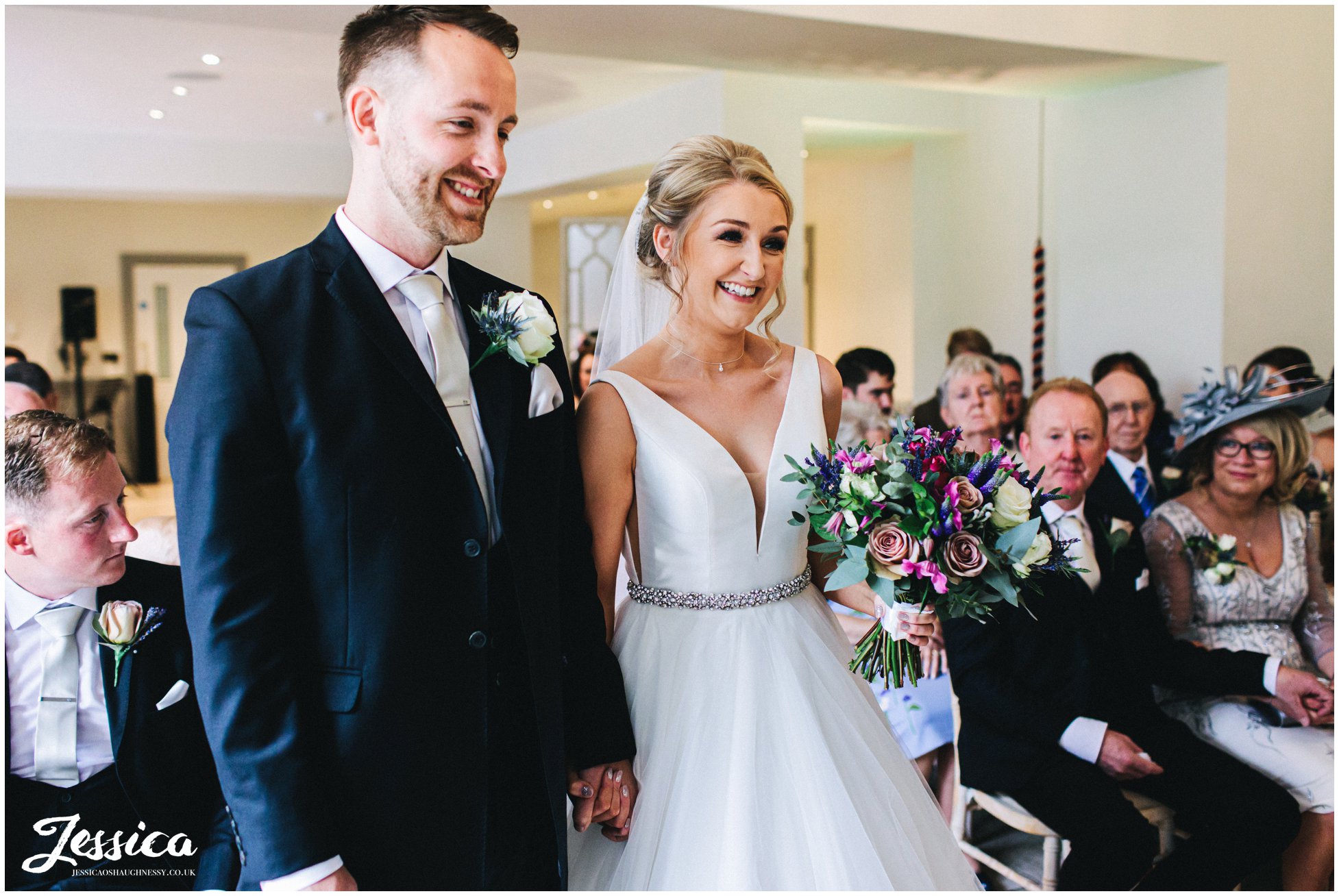 bride and groom smile during wedding ceremony in north wales