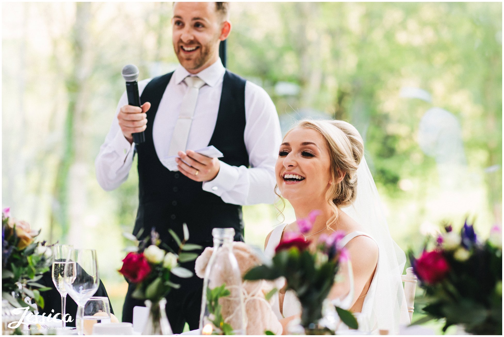 bride laughs as her new husband gives his speech at tyn dwr hall