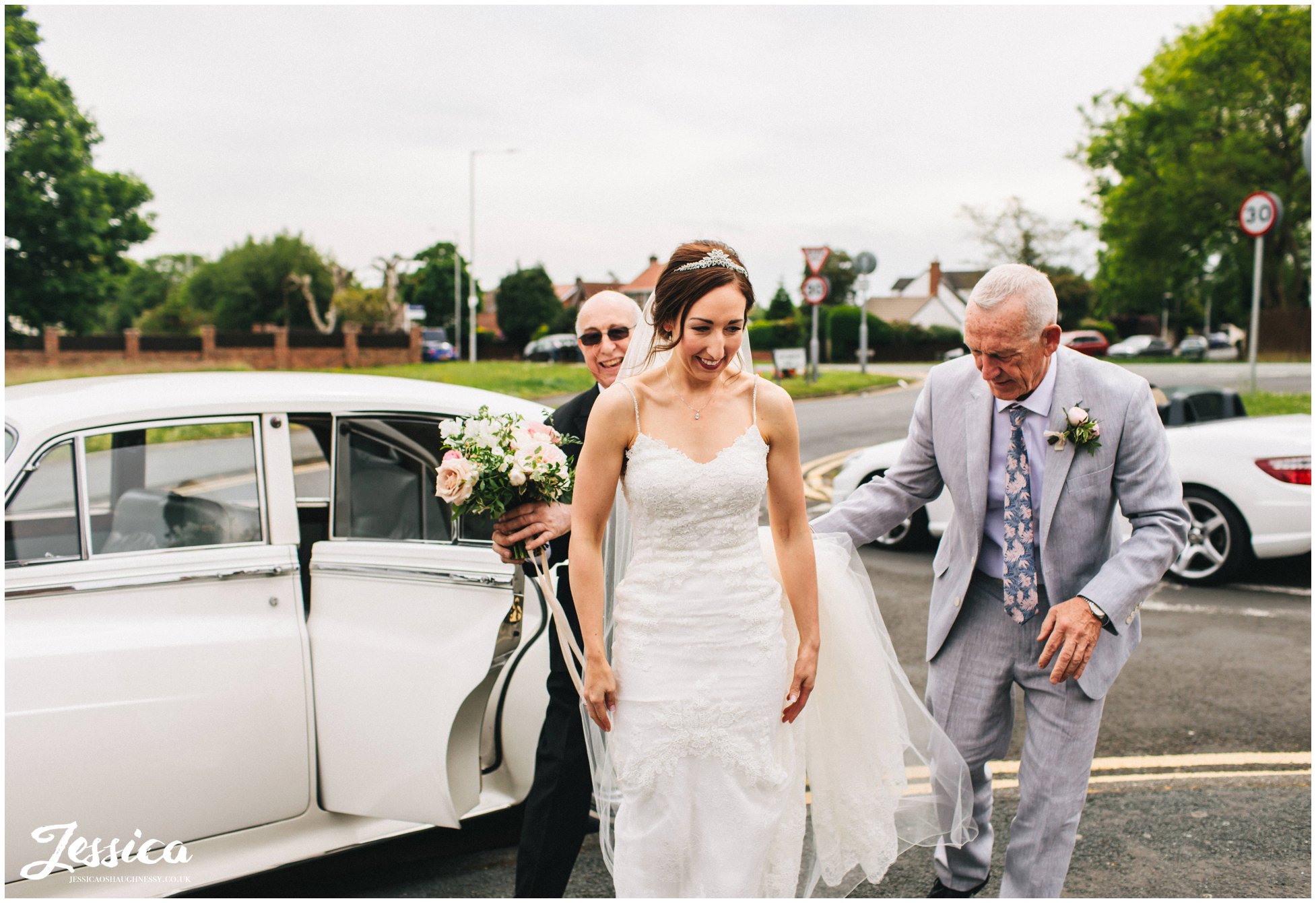 father of the bride helps his daughter out the wedding car