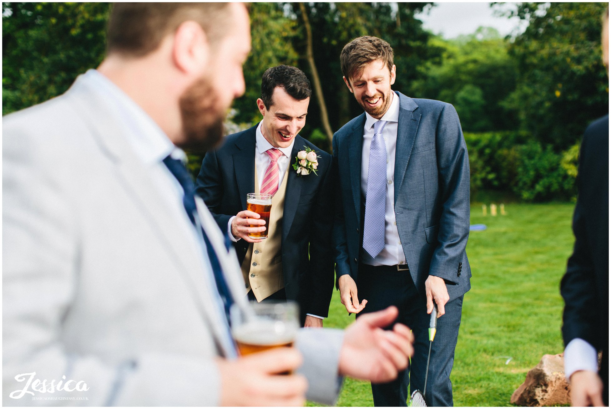 groom jokes with friends in the venue gardens