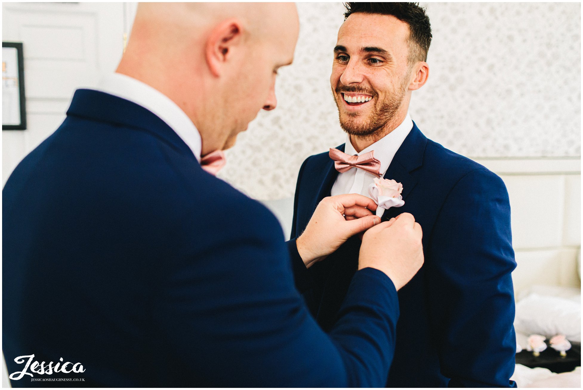 best man helps groom put on his button hole