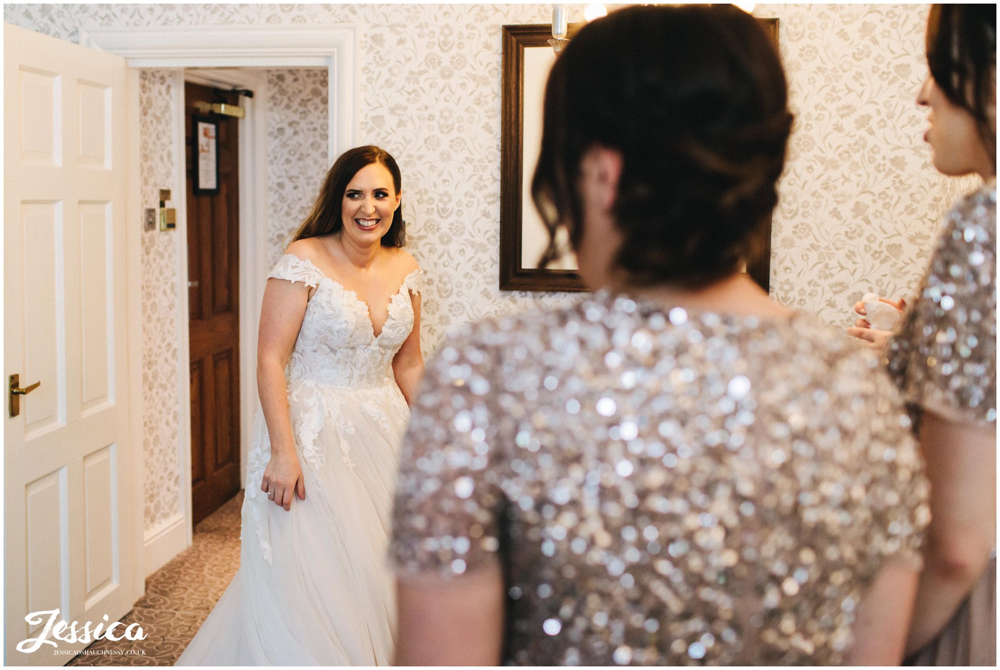 bride walks in to show her bridesmaids her wedding dress