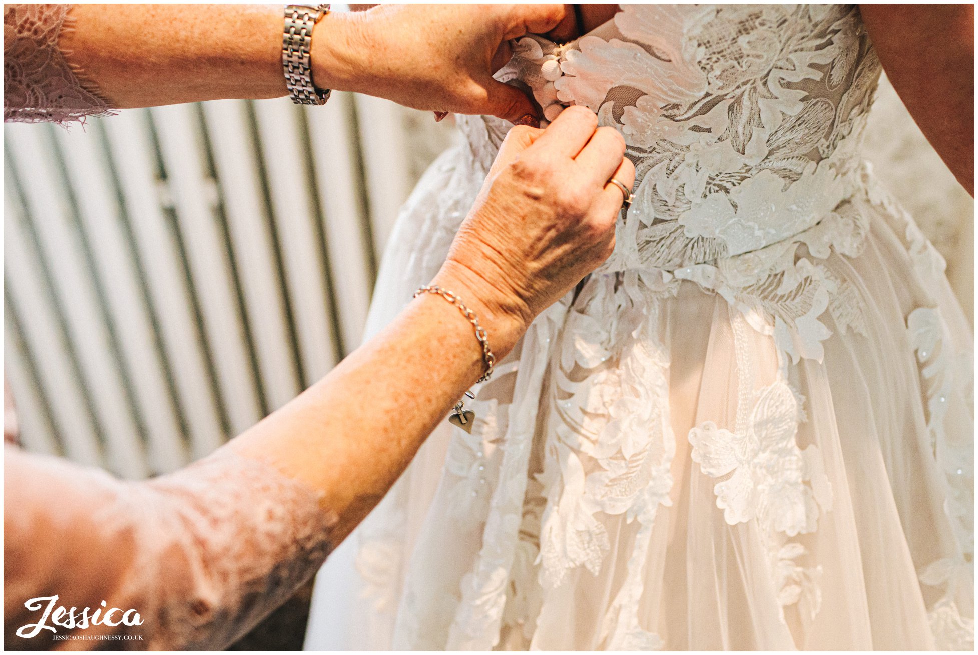 bride has dress buttoned up by her mum before the ceremony