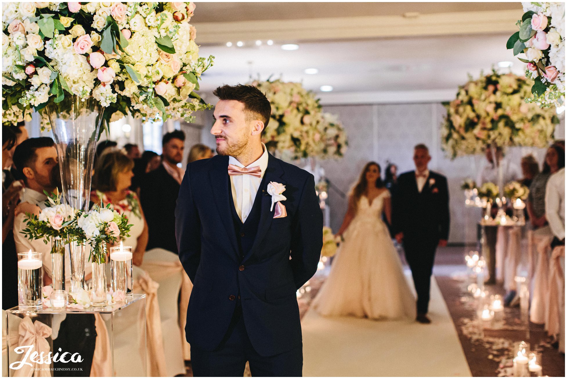 groom awaits his bride as she walks down the aisle