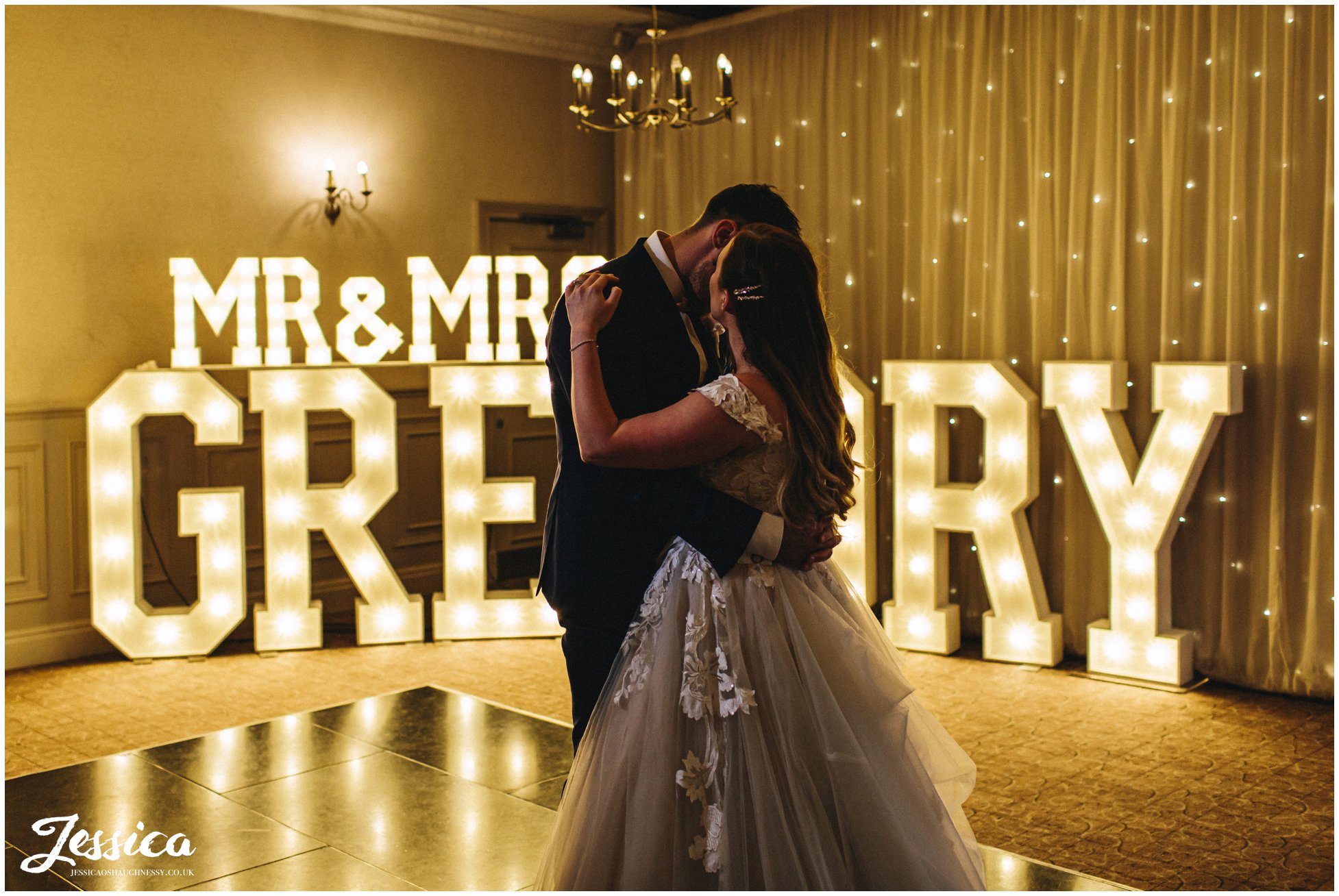 couple share their first dance together in front of love lights