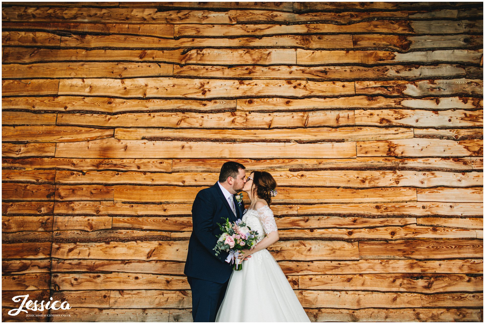 couple kiss under tower hill barns bridge