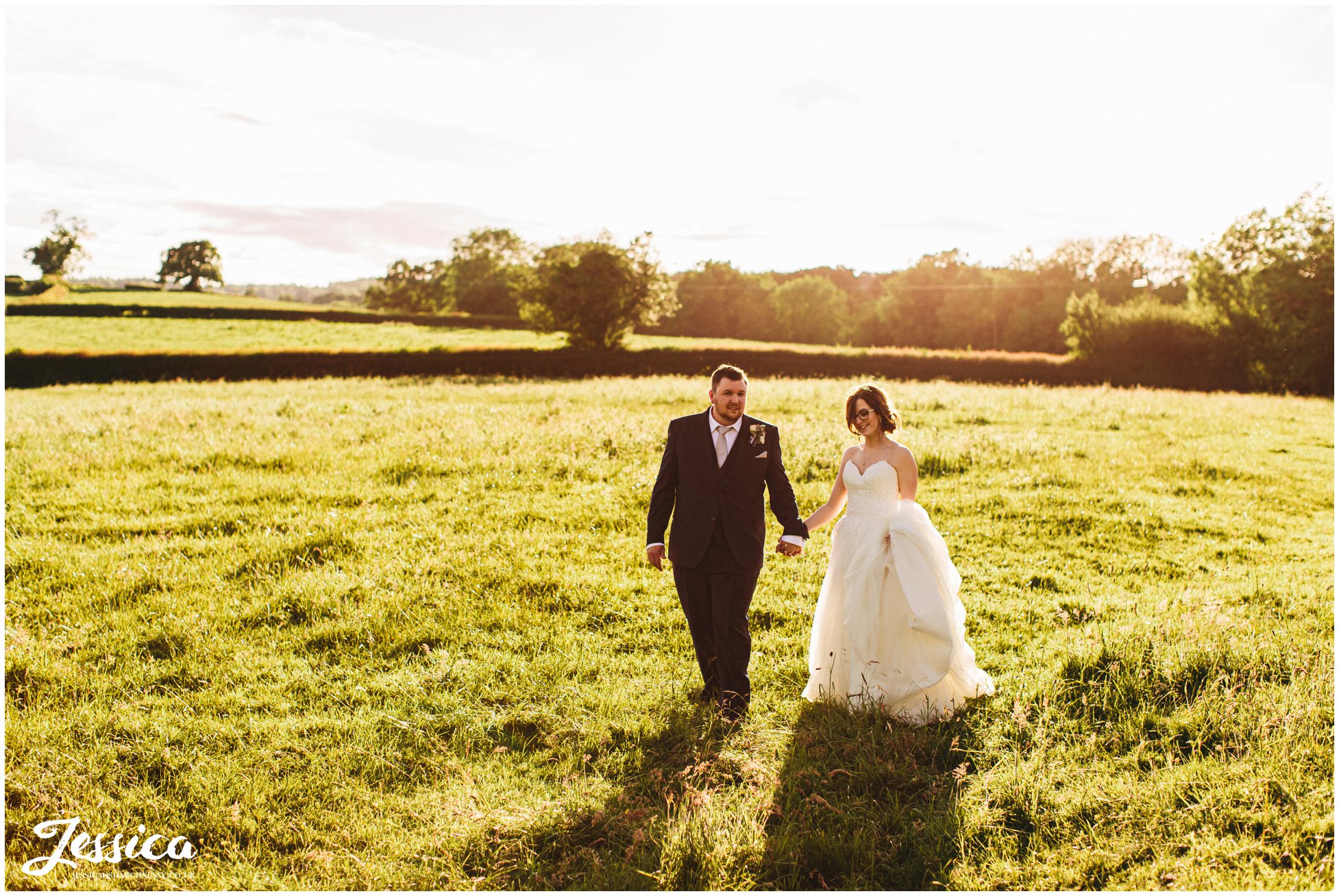 husband and wife walk through fields surrounding the north wales wedding venue
