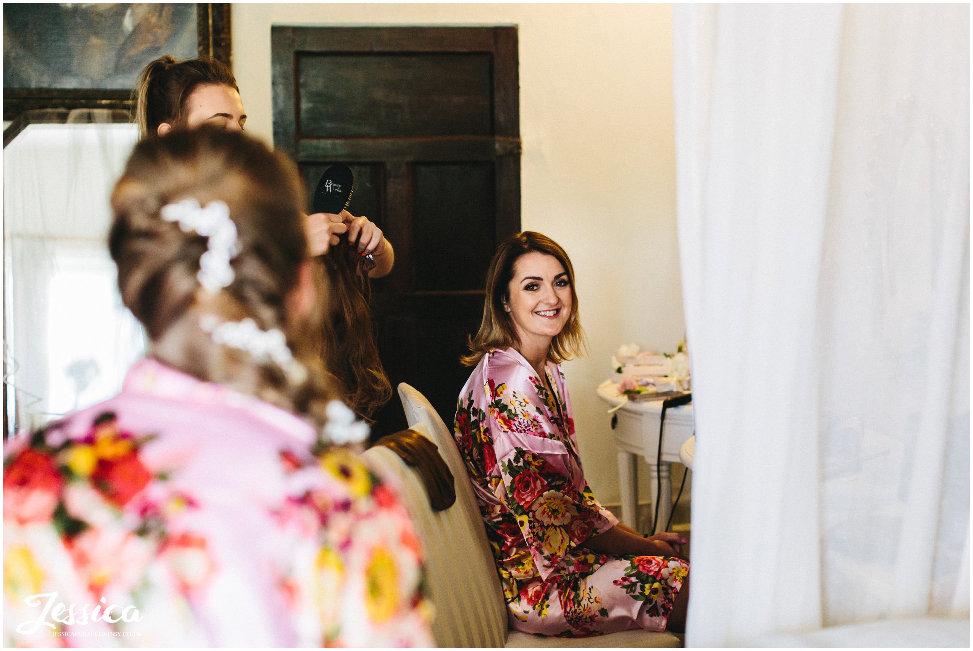 bride gets her hair done on the wedding morning at eyam hall in derbyshire