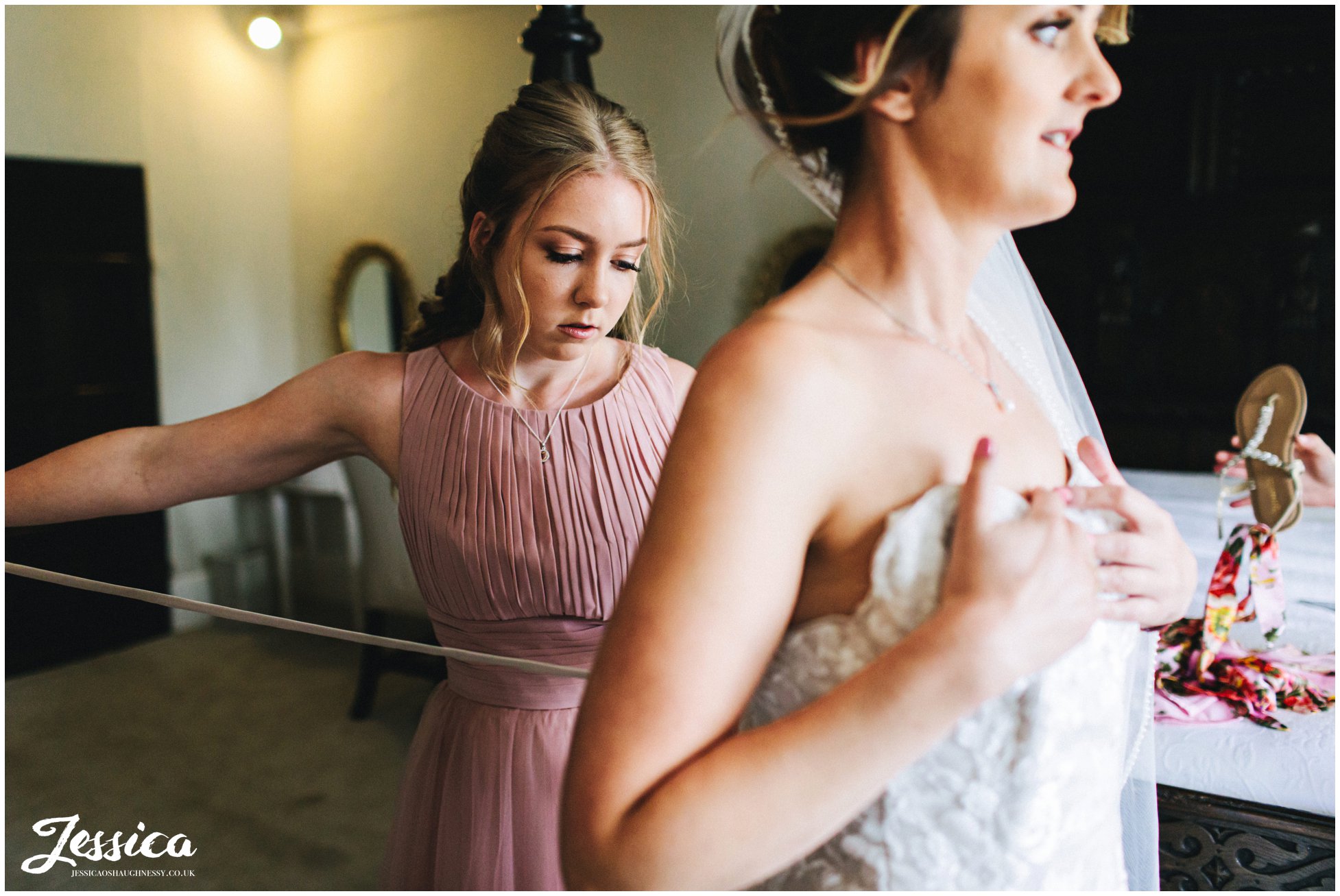 grooms daughter helps bride into her dress