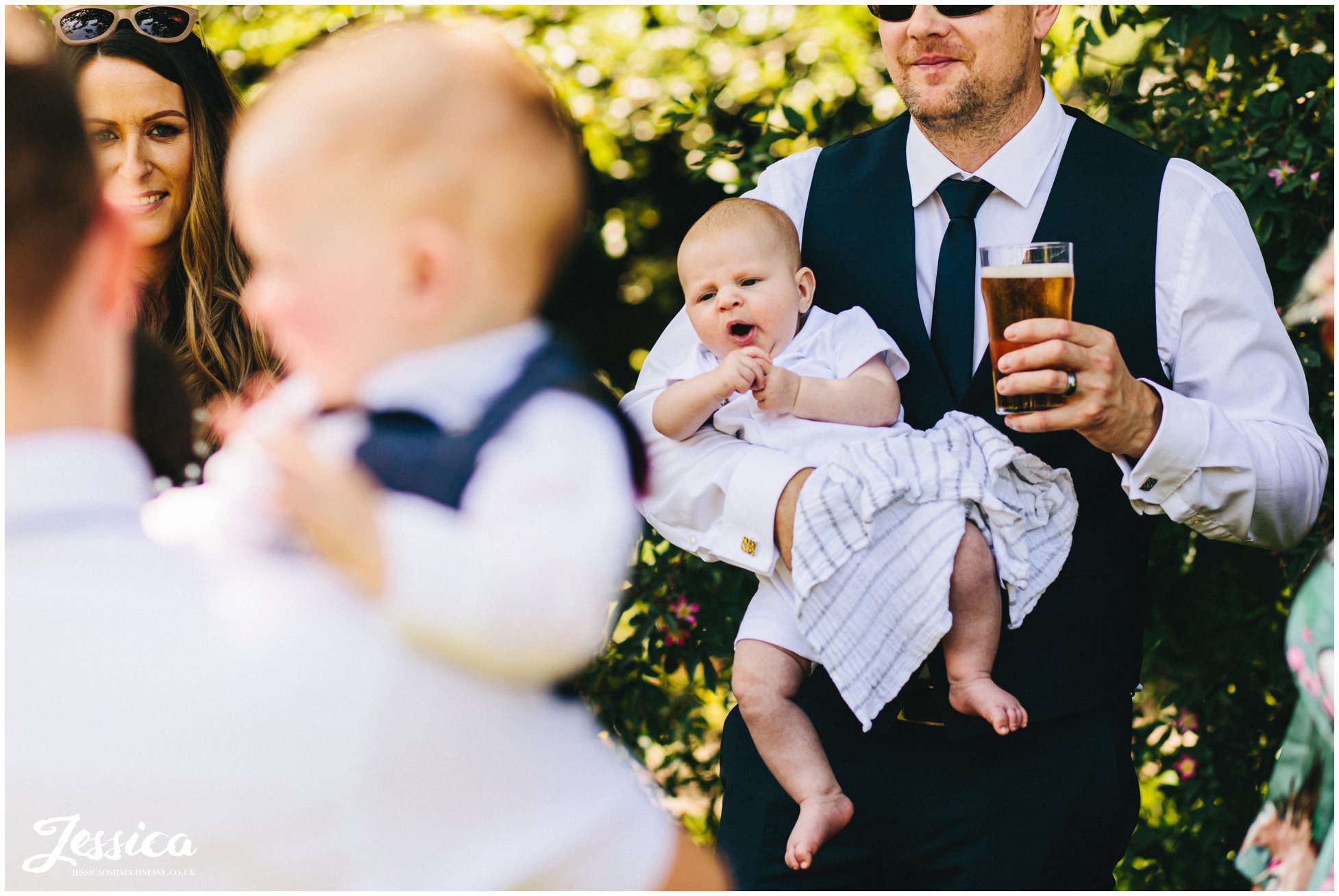 guest holds baby &amp; beer during the festivities