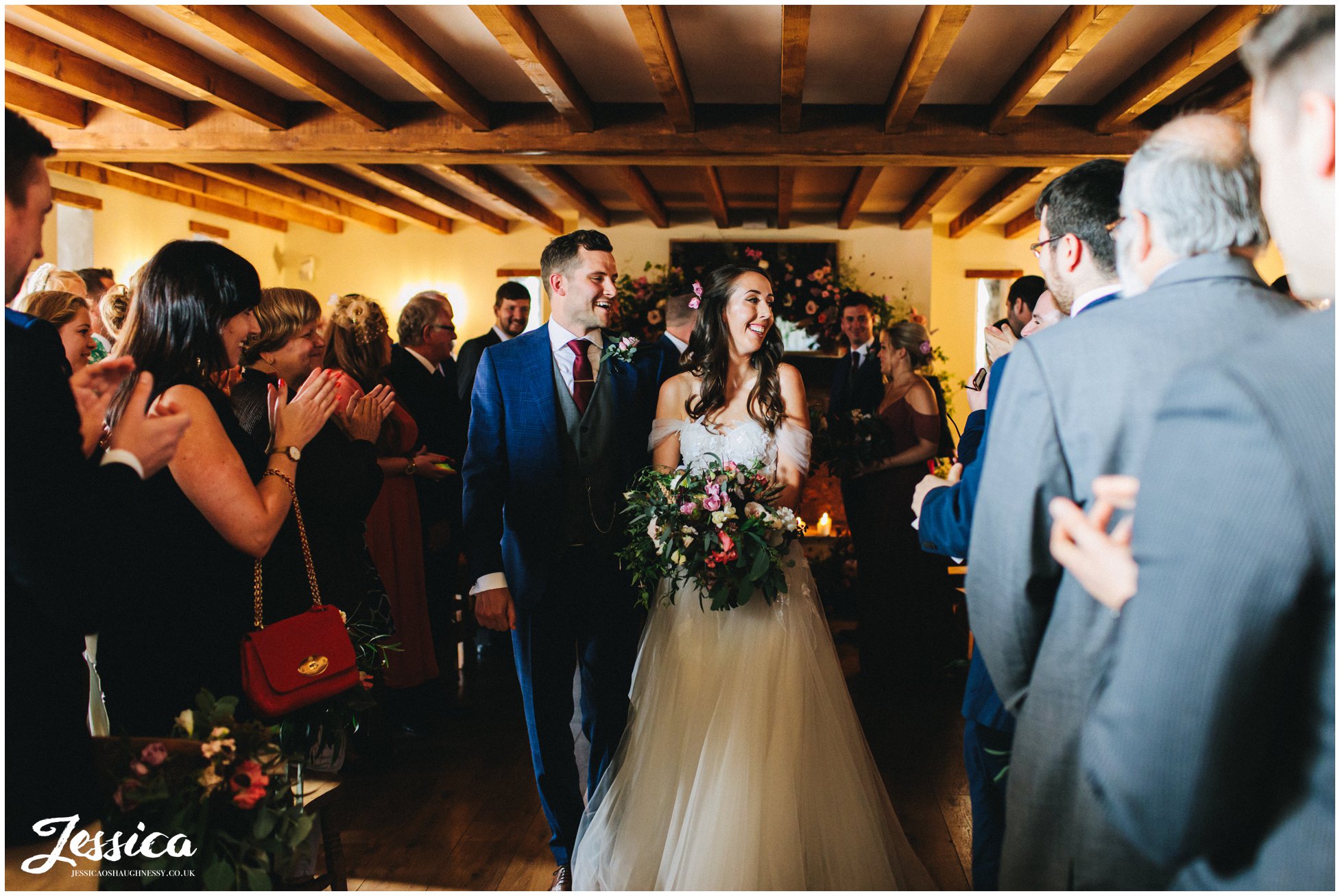 the guests applaud the couple as they walk out as husband and wife