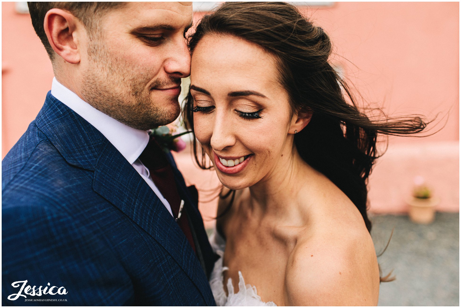 couple stand in front of pink farmhouse at the outbuildings