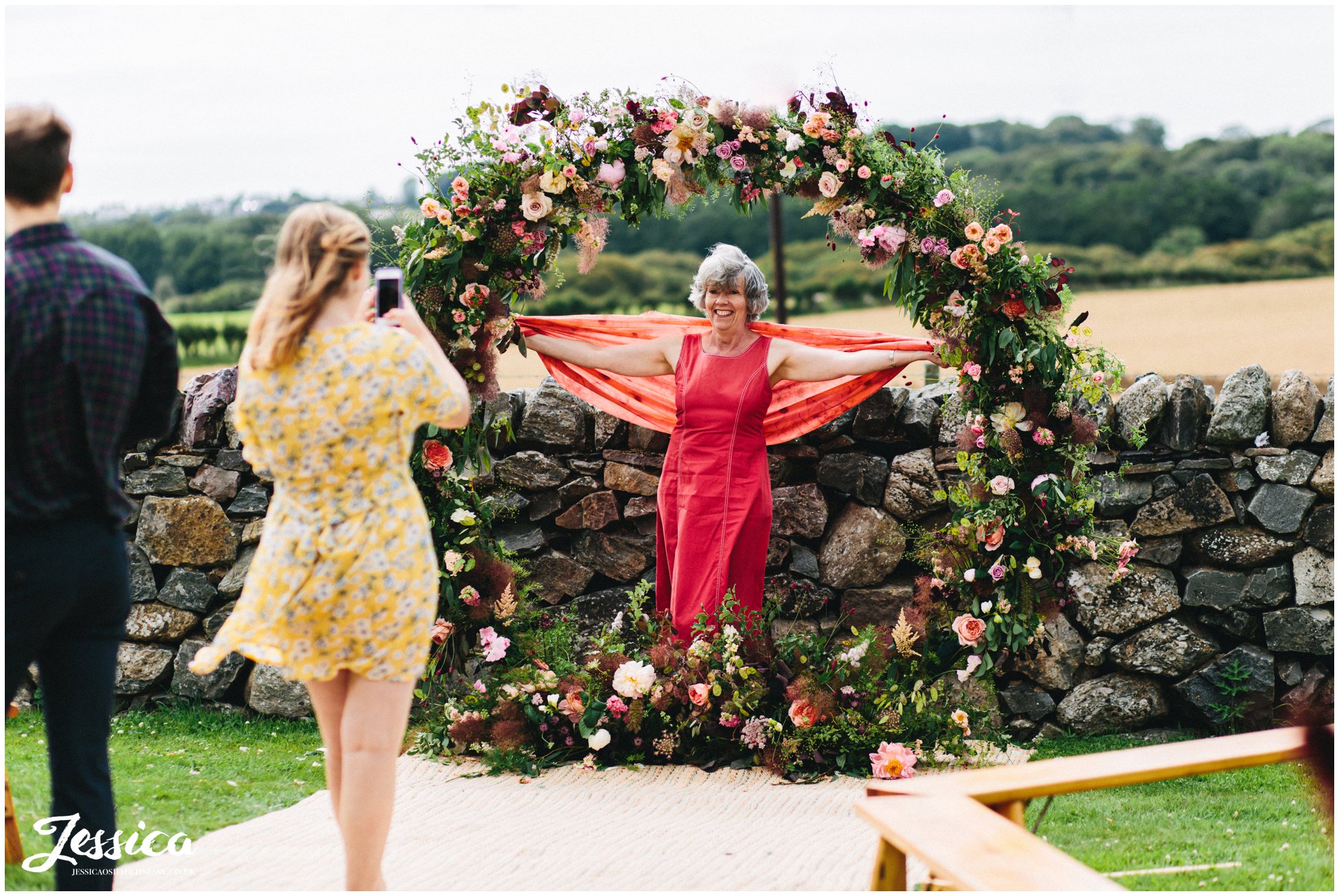 guests pose with the floral arch at the outbuildings, anglesey
