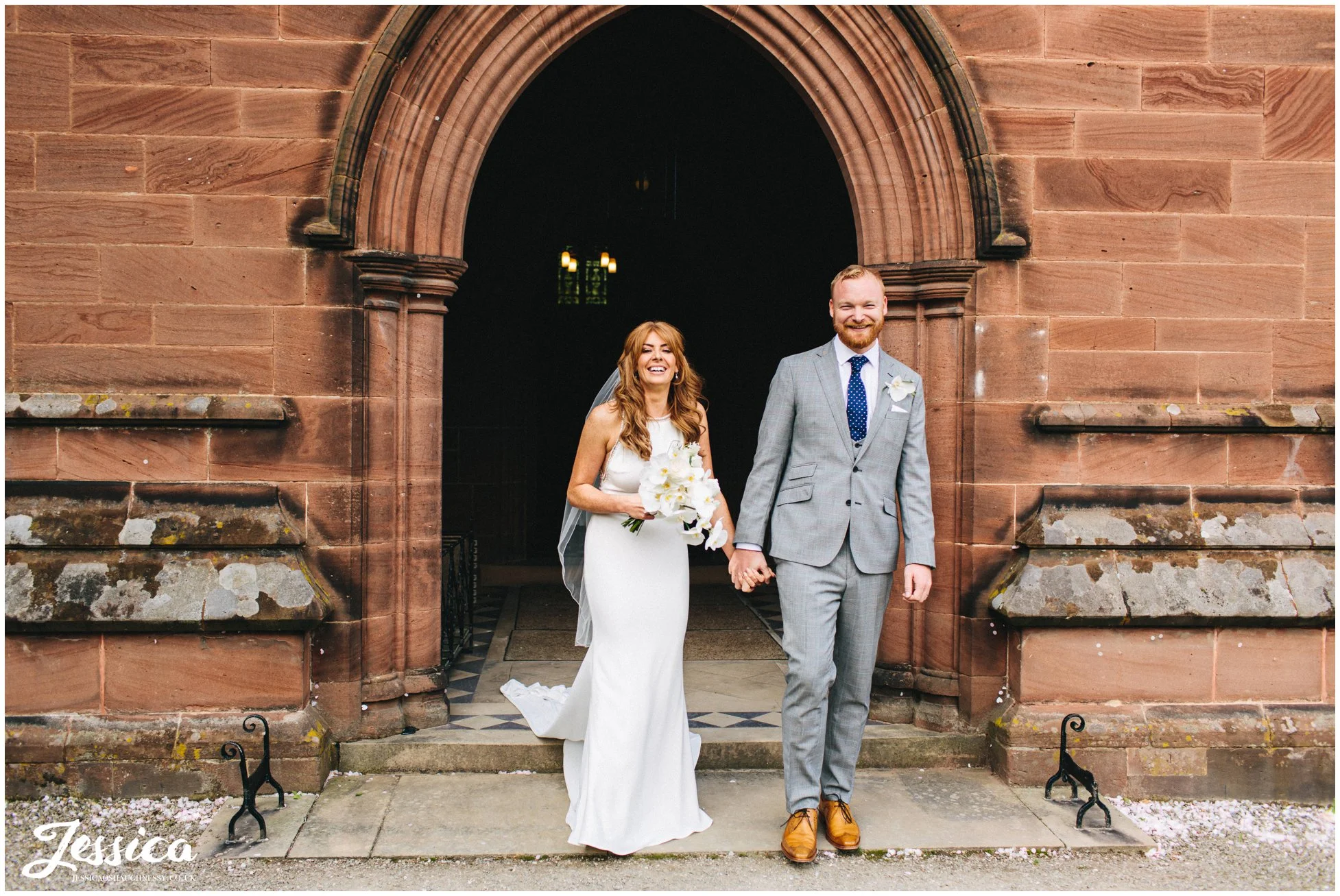 couple smile as they walk out of the church as a married couple