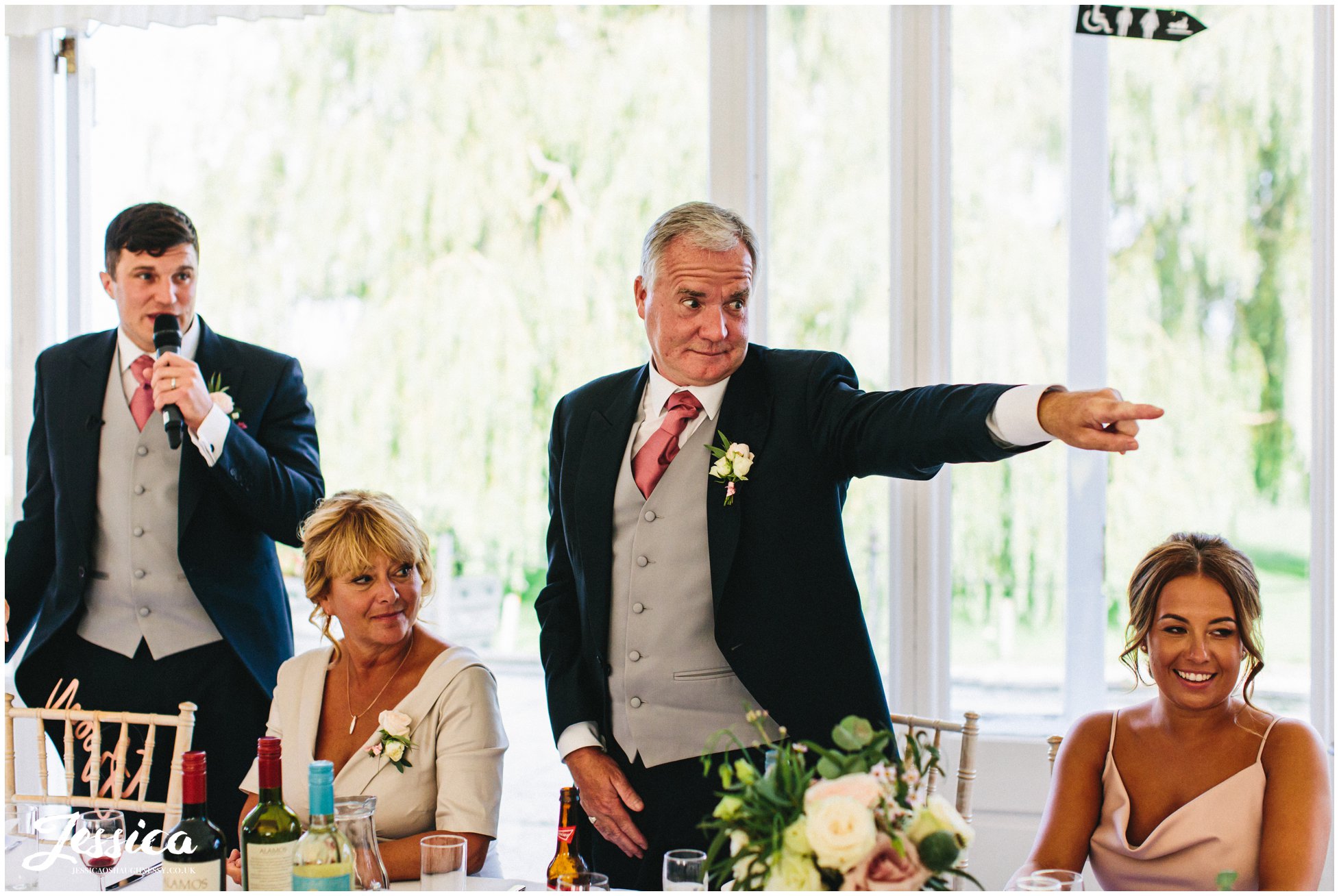 father of the groom points to guests 