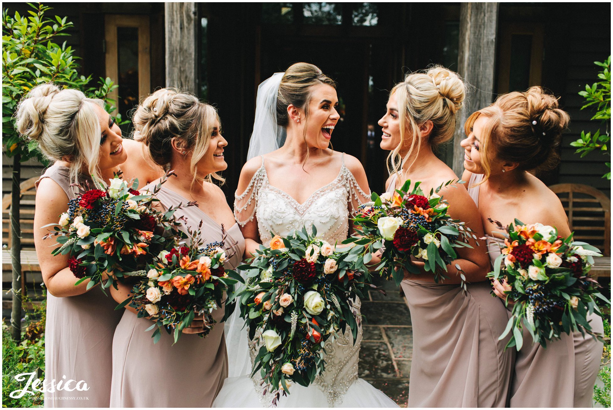 bride laughs with her bridesmaids outside the oak tree of peover