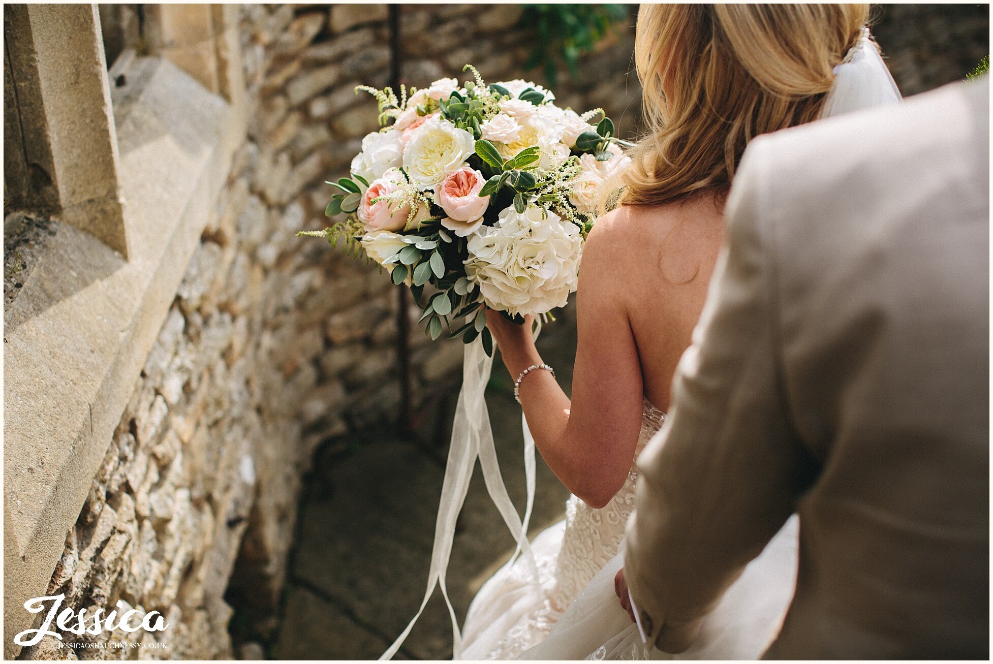 bride carries boho bouquet tied with ribbons