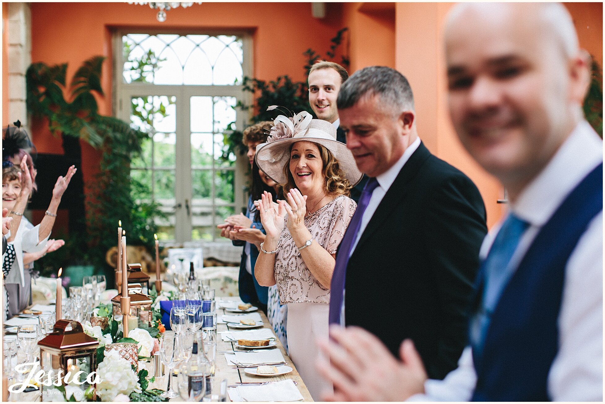 mother of the groom claps as couple enter