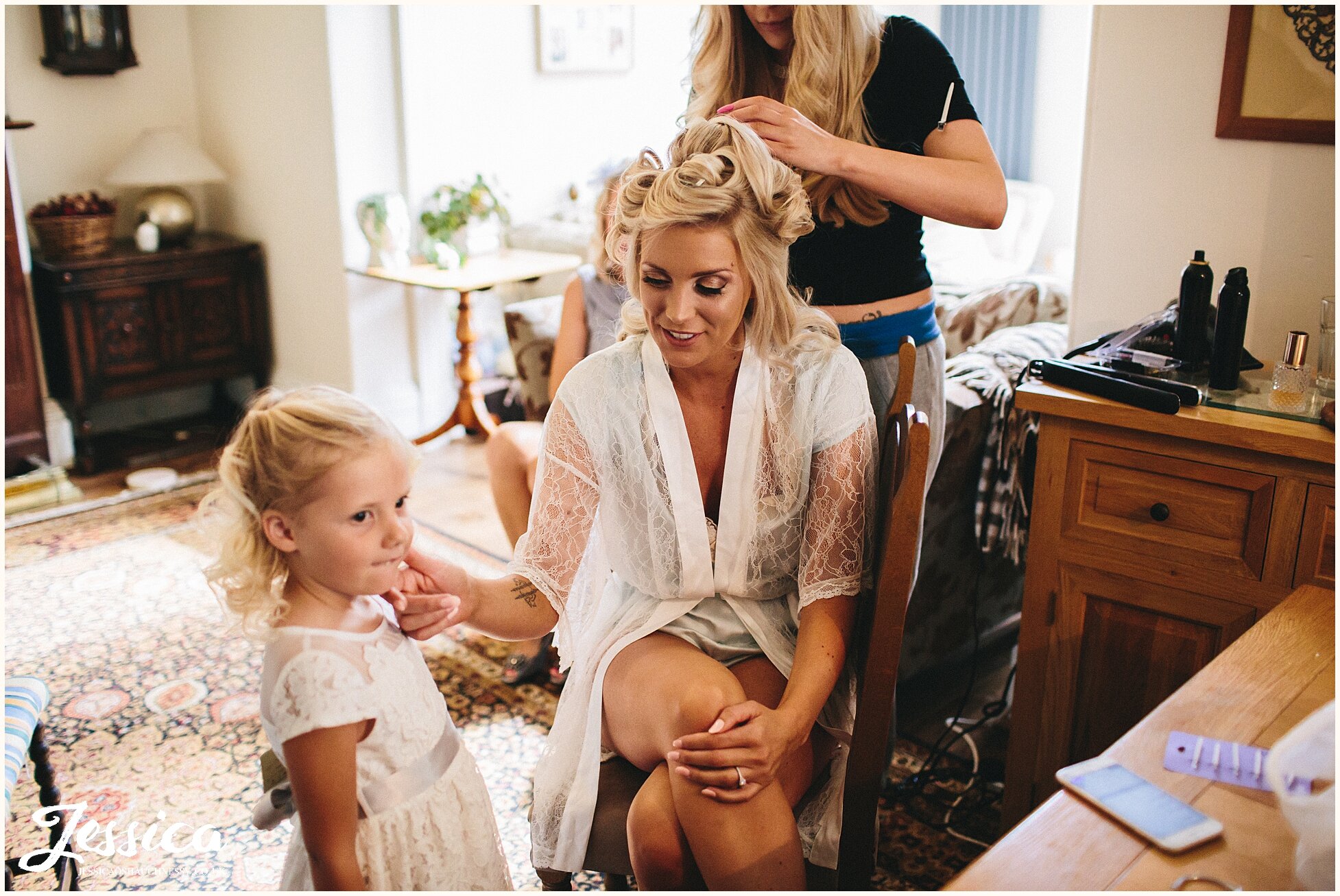 bride gets hair done whilst playing with flower girl