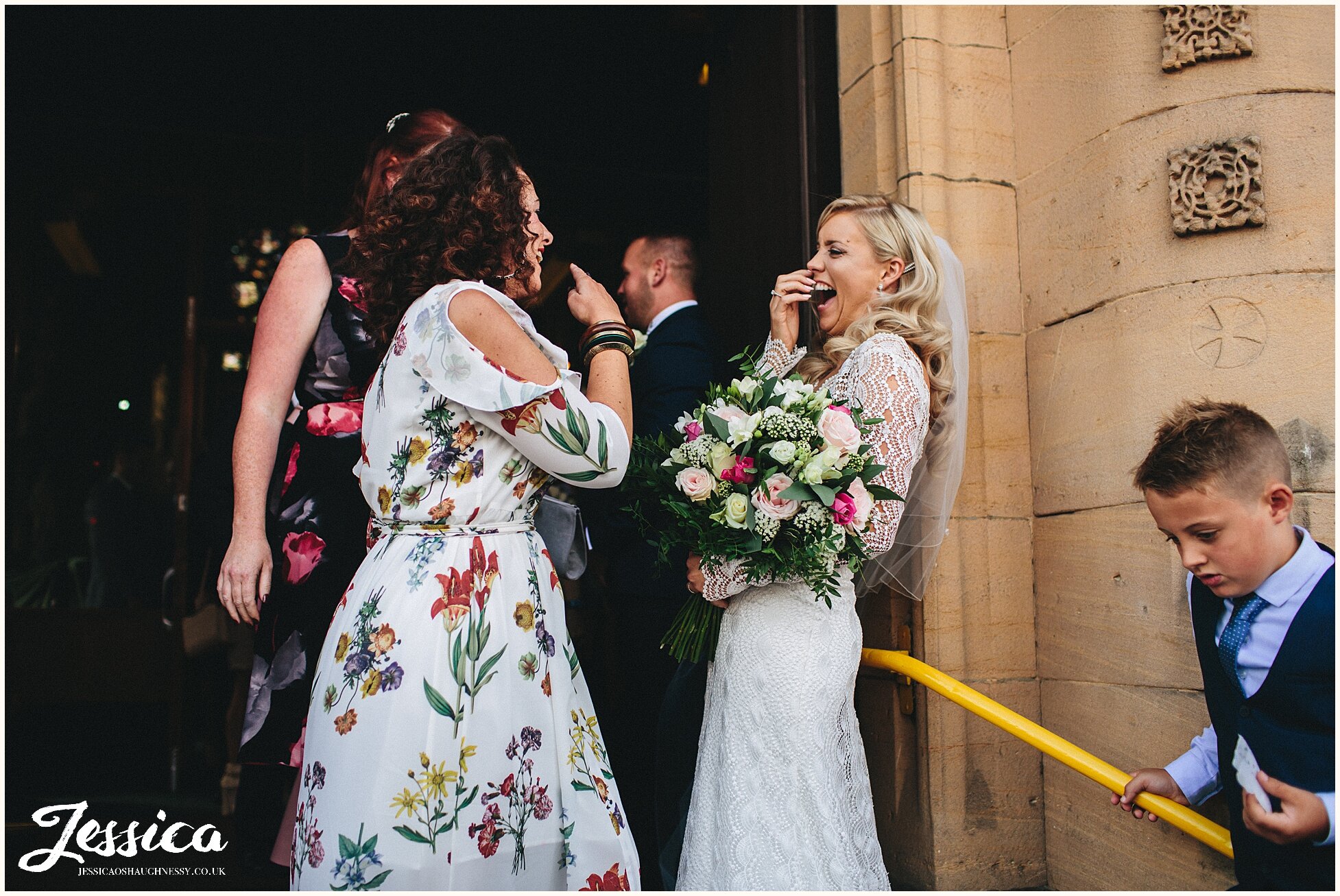 bride laughs with friend outside st annes church