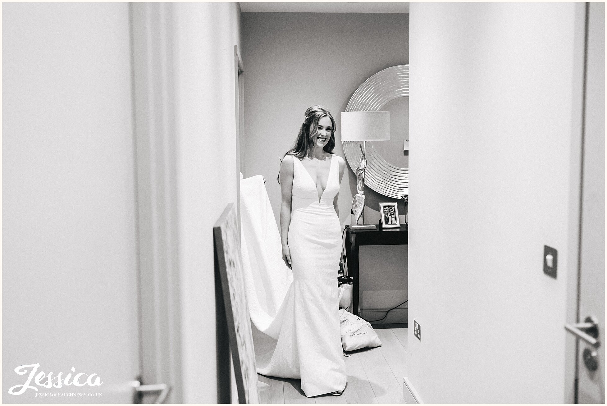 bride walks out of her bedroom, dressed for her wedding