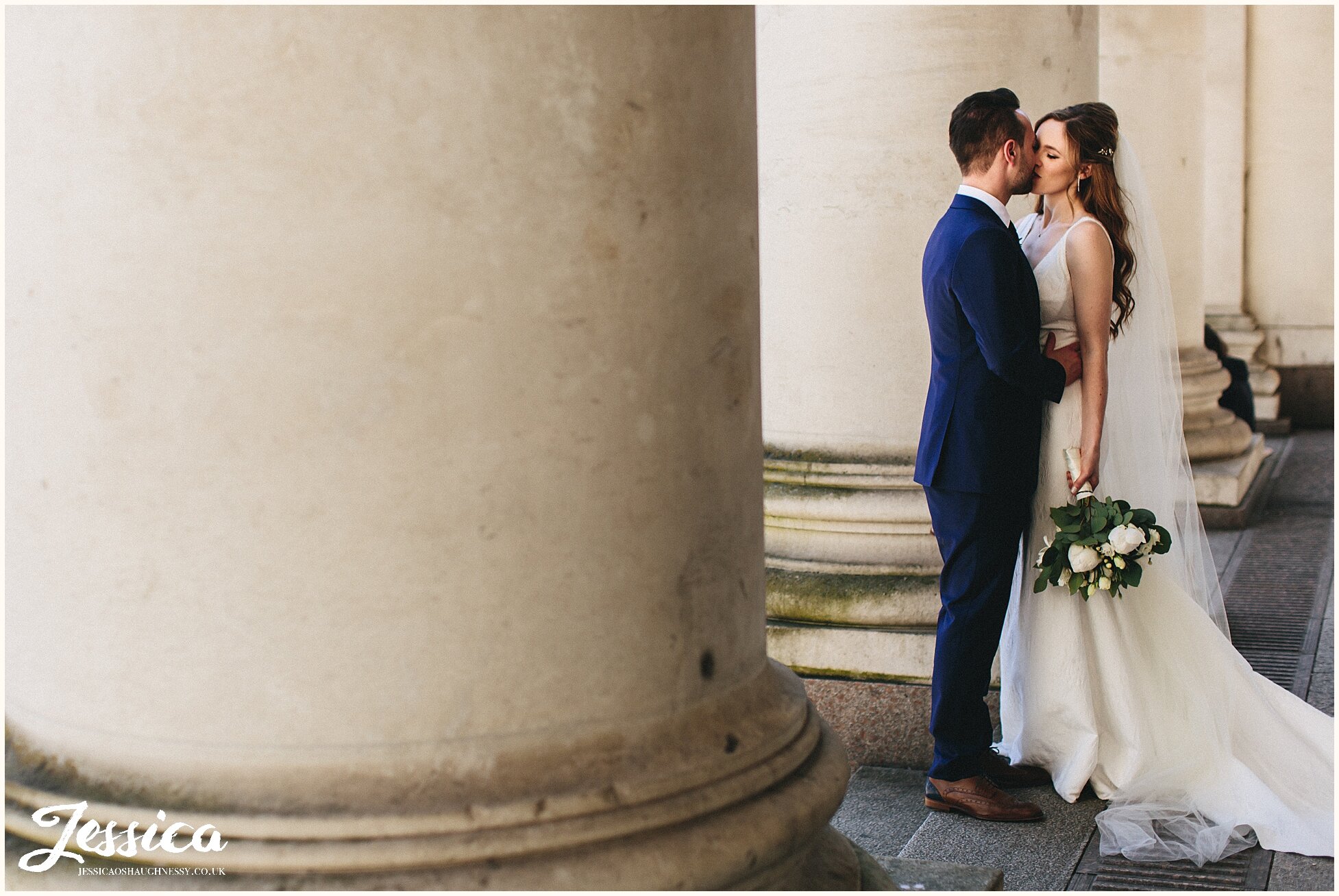 newly wed's kissing between the columns in manchester city centre
