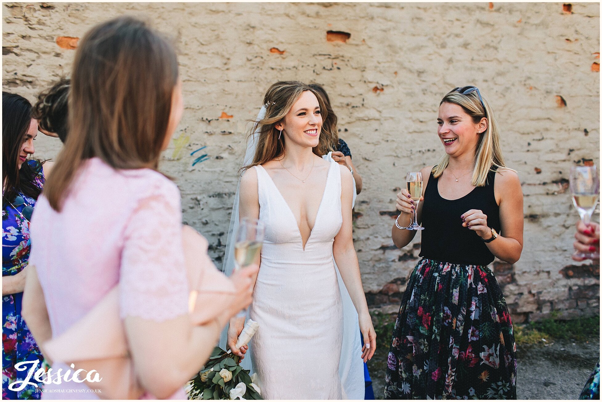 bride laughs with her friends at her wedding reception