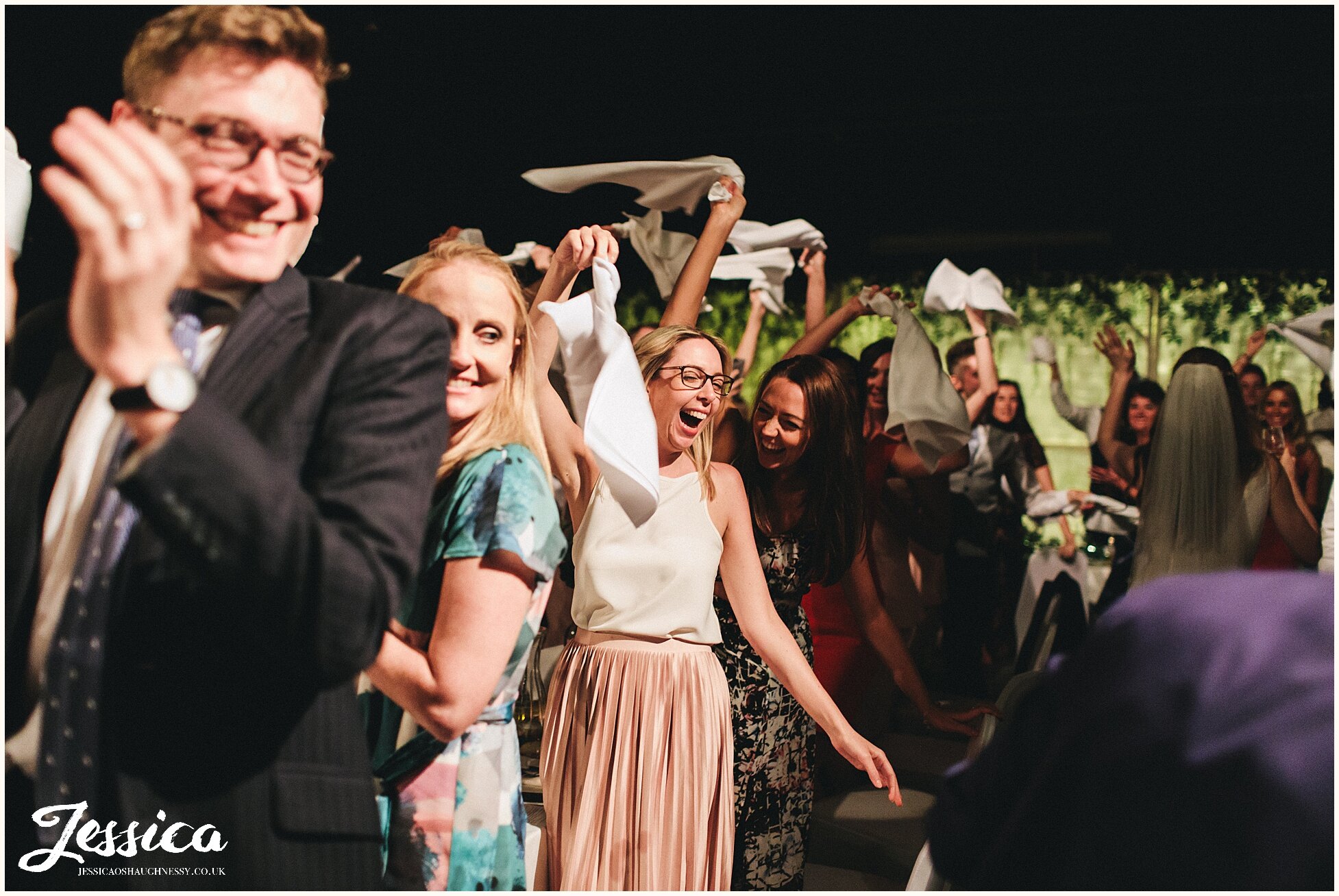 wedding guests swing napkins round as the bride &amp; groom walk past