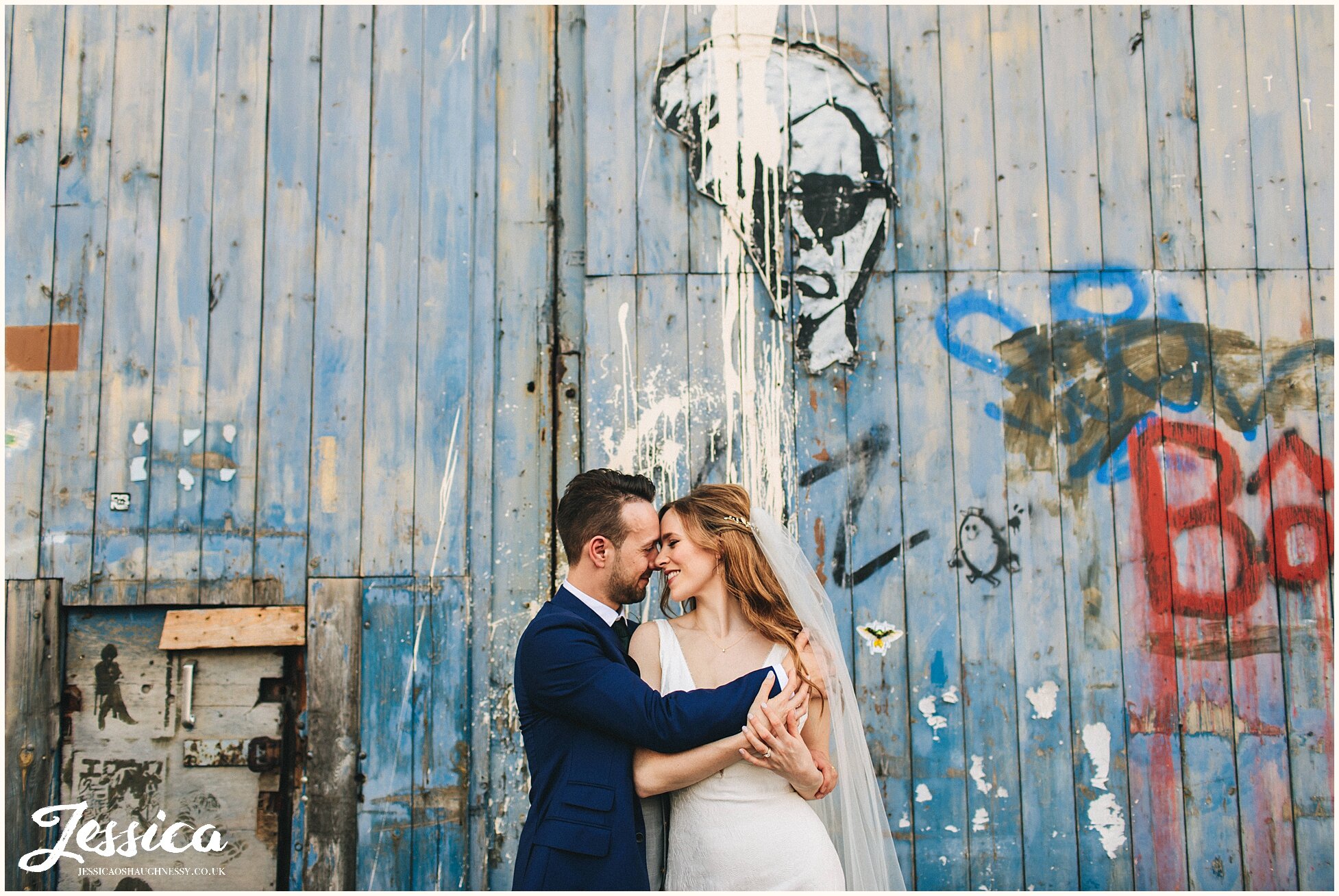 newly wed's embrace in front of blue graffitied door