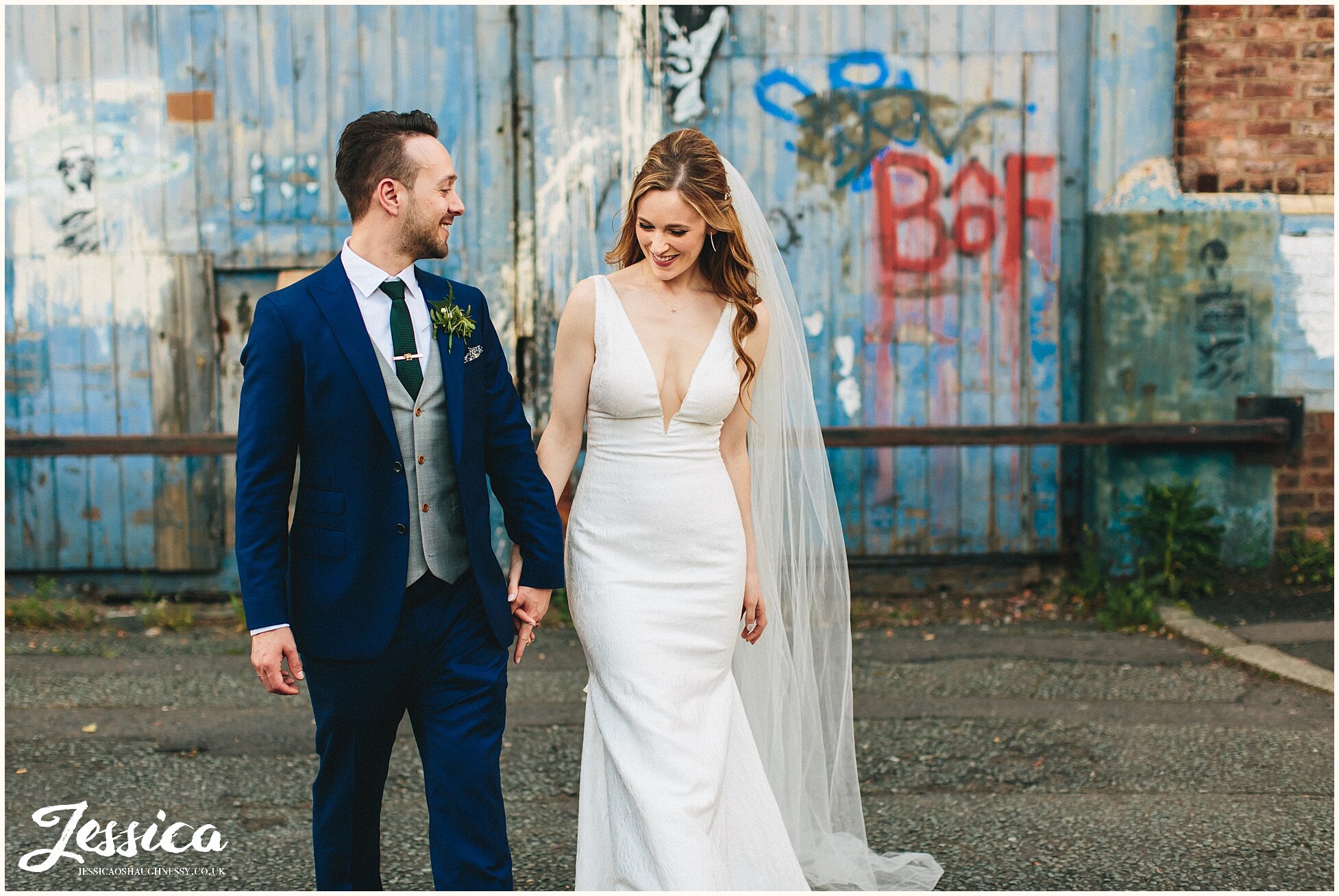 newly wed's hold hands as they walk on the manchester streets