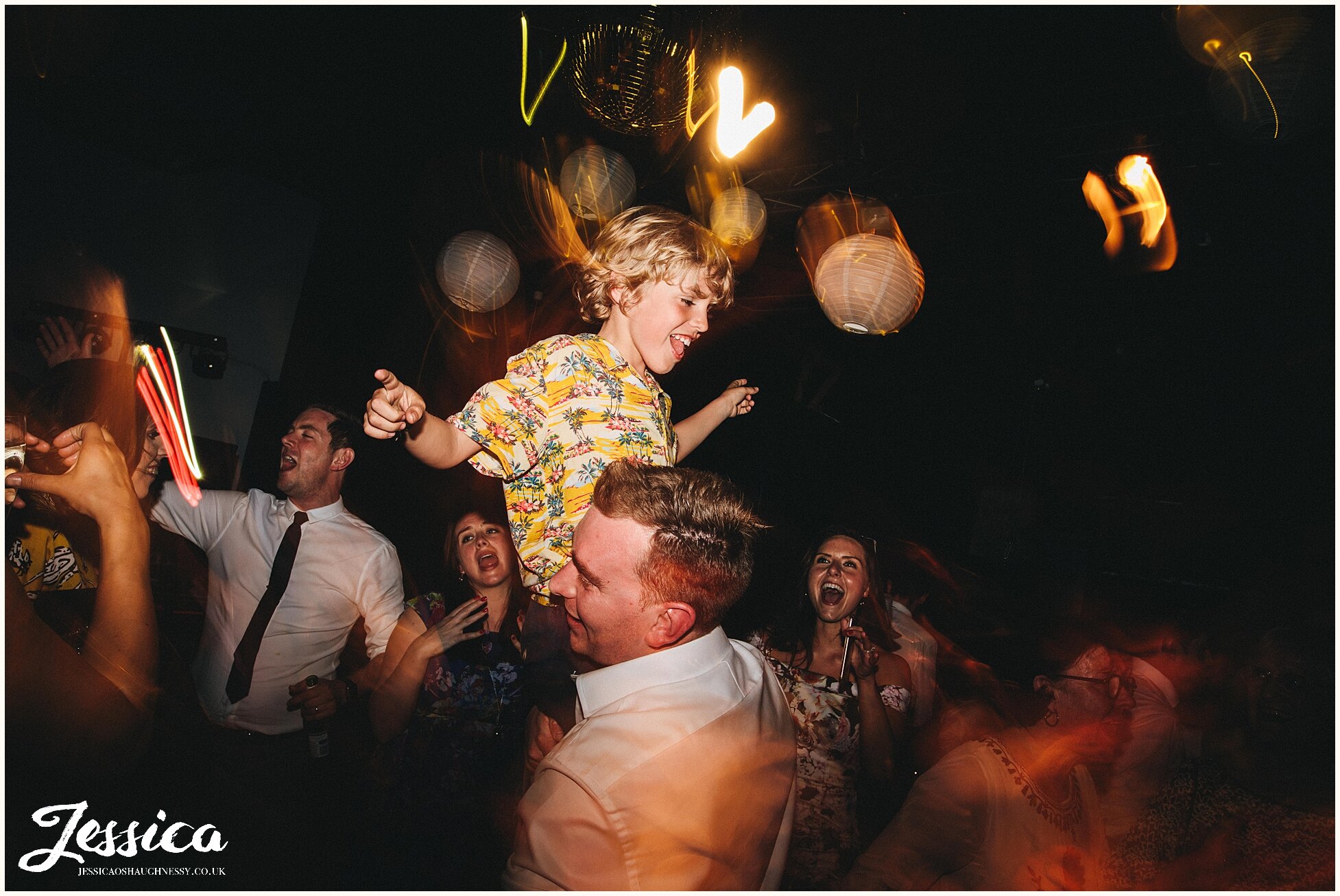 child on the shoulders of wedding guest