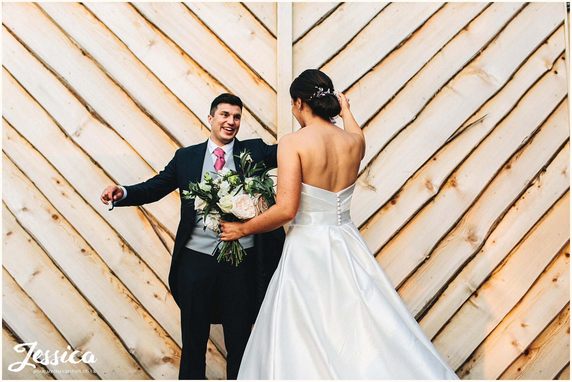 new couple dance in front of rustic barn doors