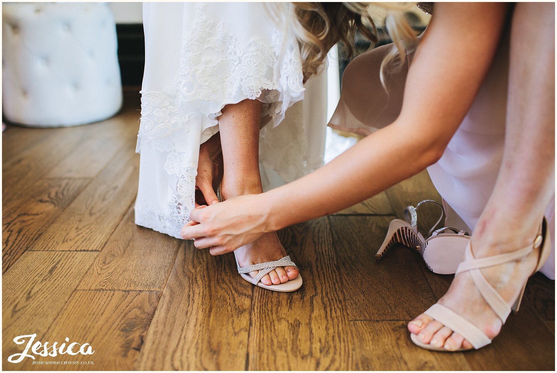 maid of honour puts the brides shoes on for her