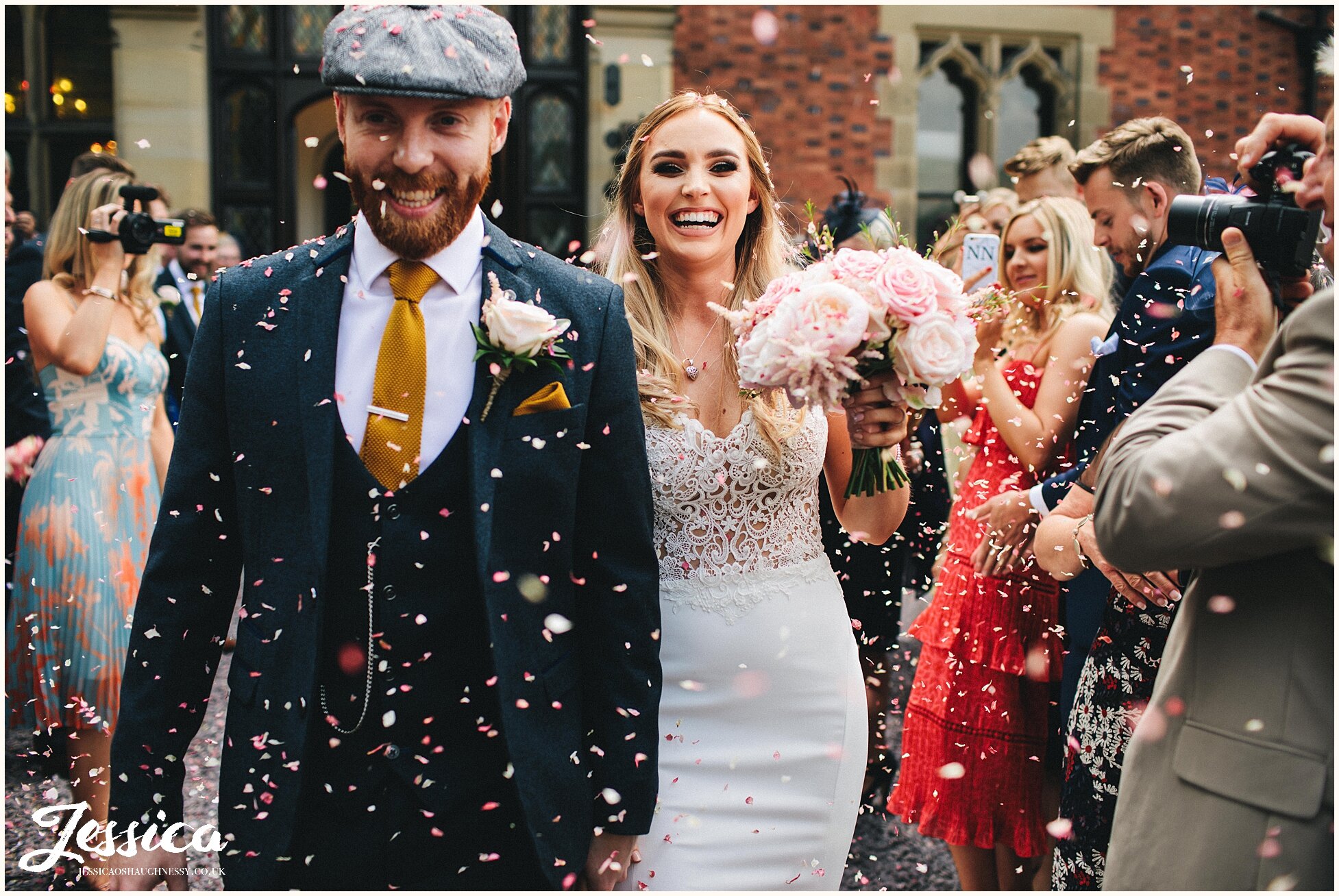 bride and groom look happy whilst being showered in confetti