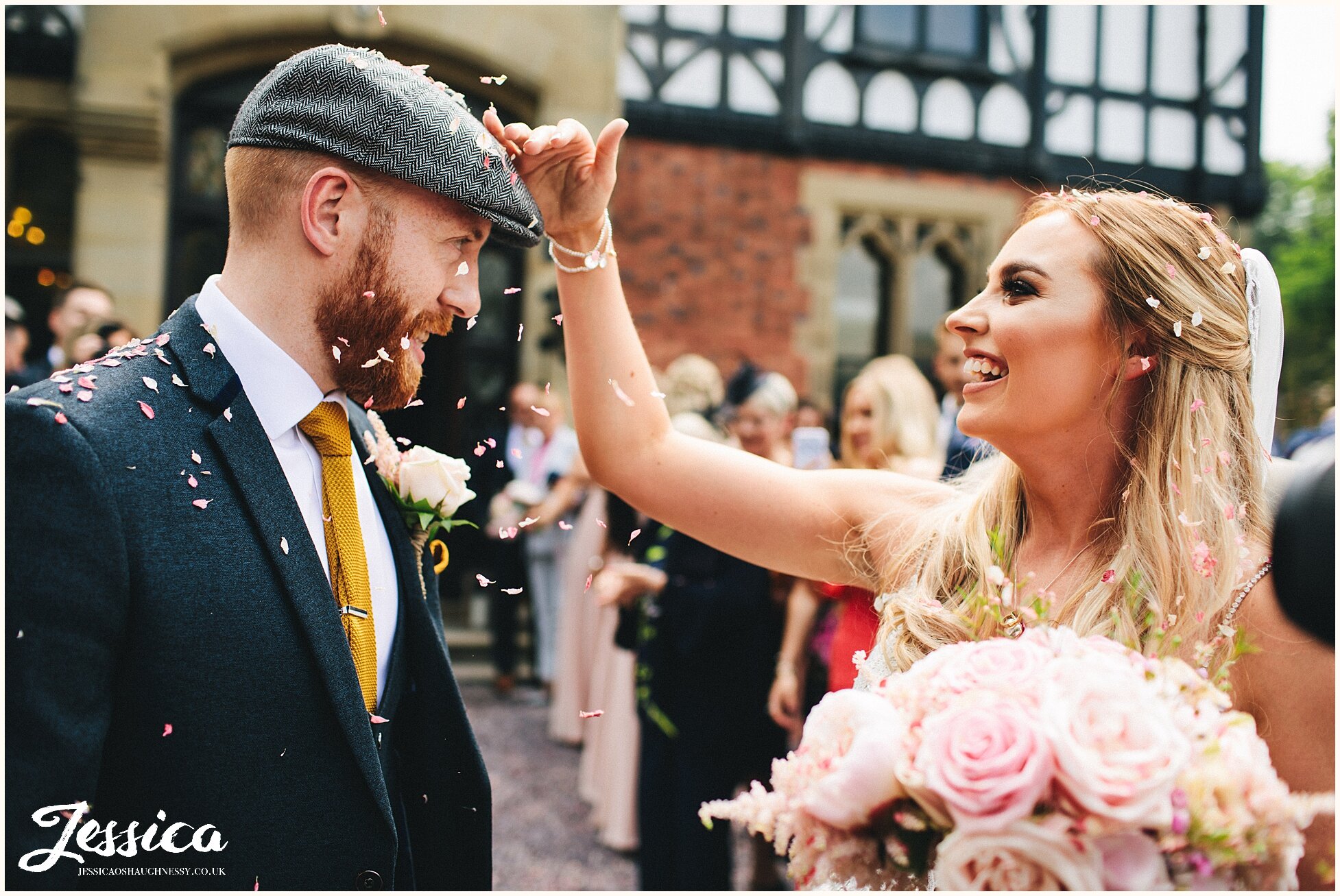 bride brushes confetti of the grooms hat