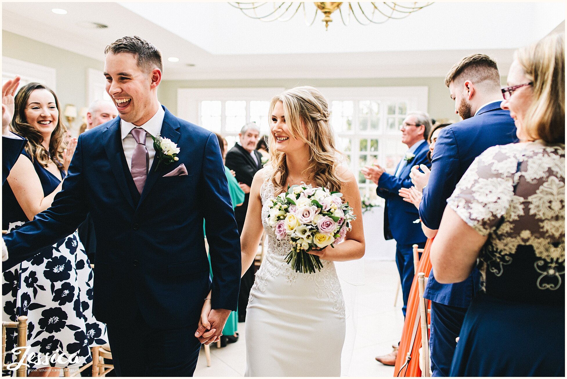 guests cheer as the couple walk out the orangery at Willington Hall