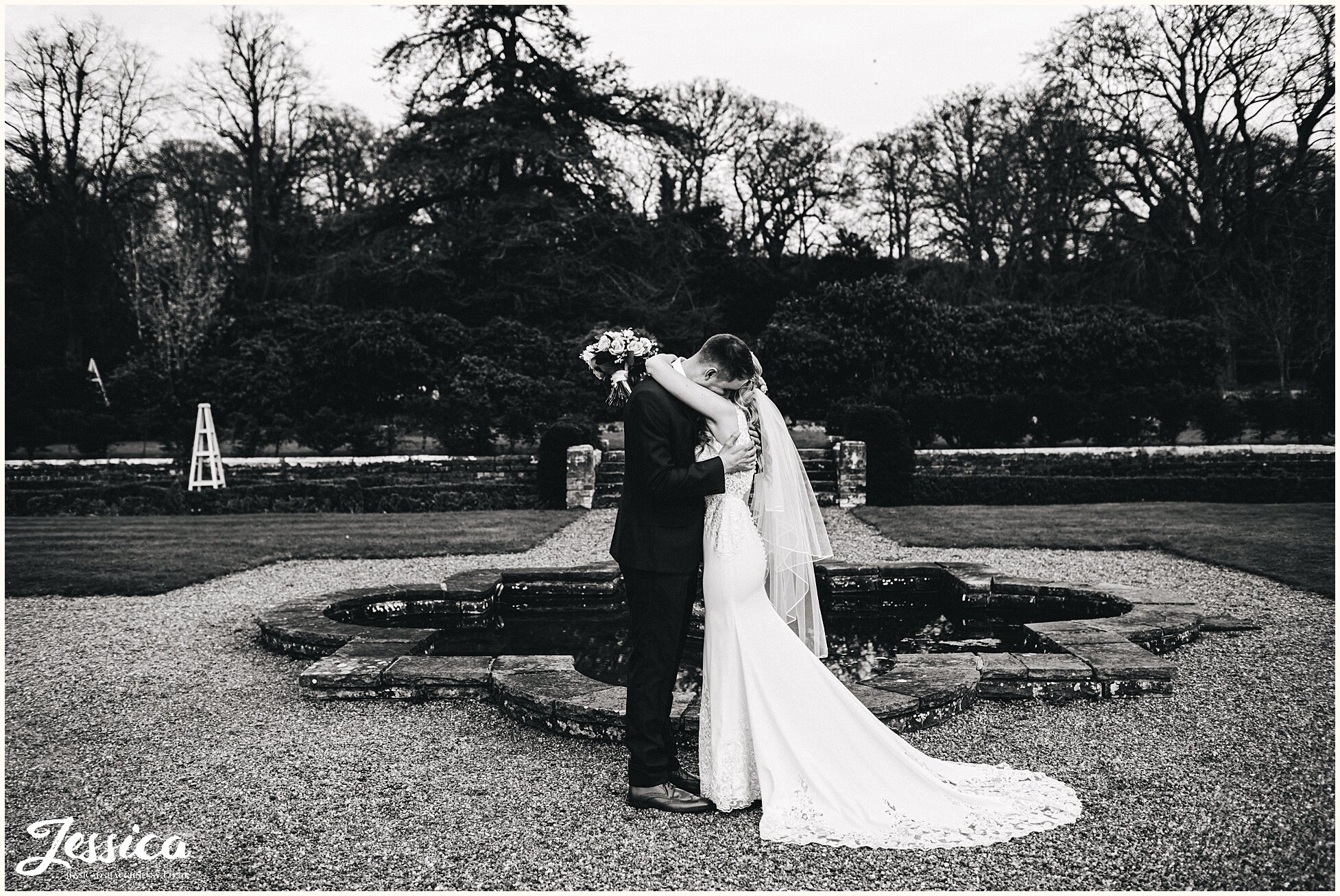 couple embrace in front of the fountain in Willington Hall grounds