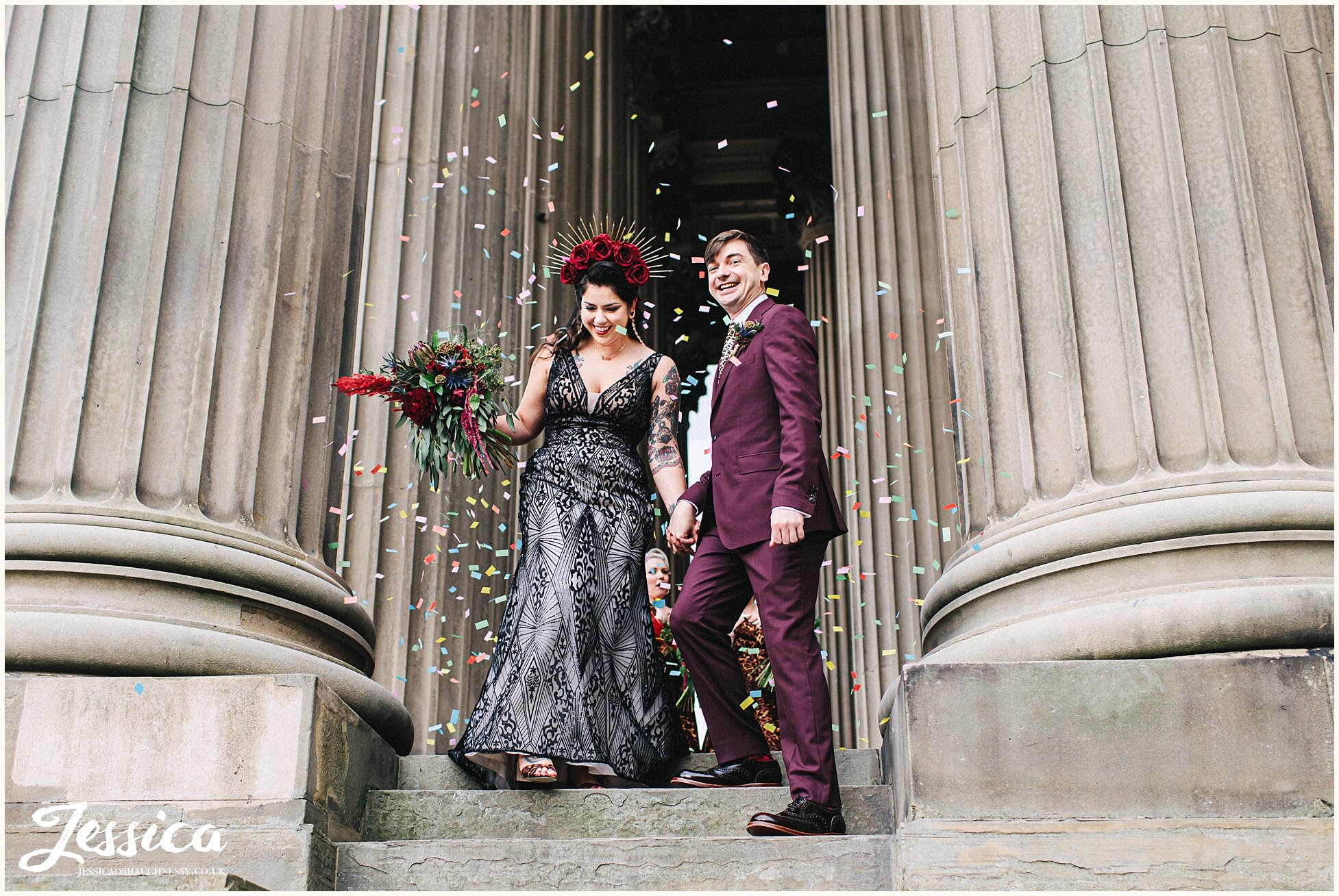 bride &amp; groom are showered in confetti between the columns of st georges