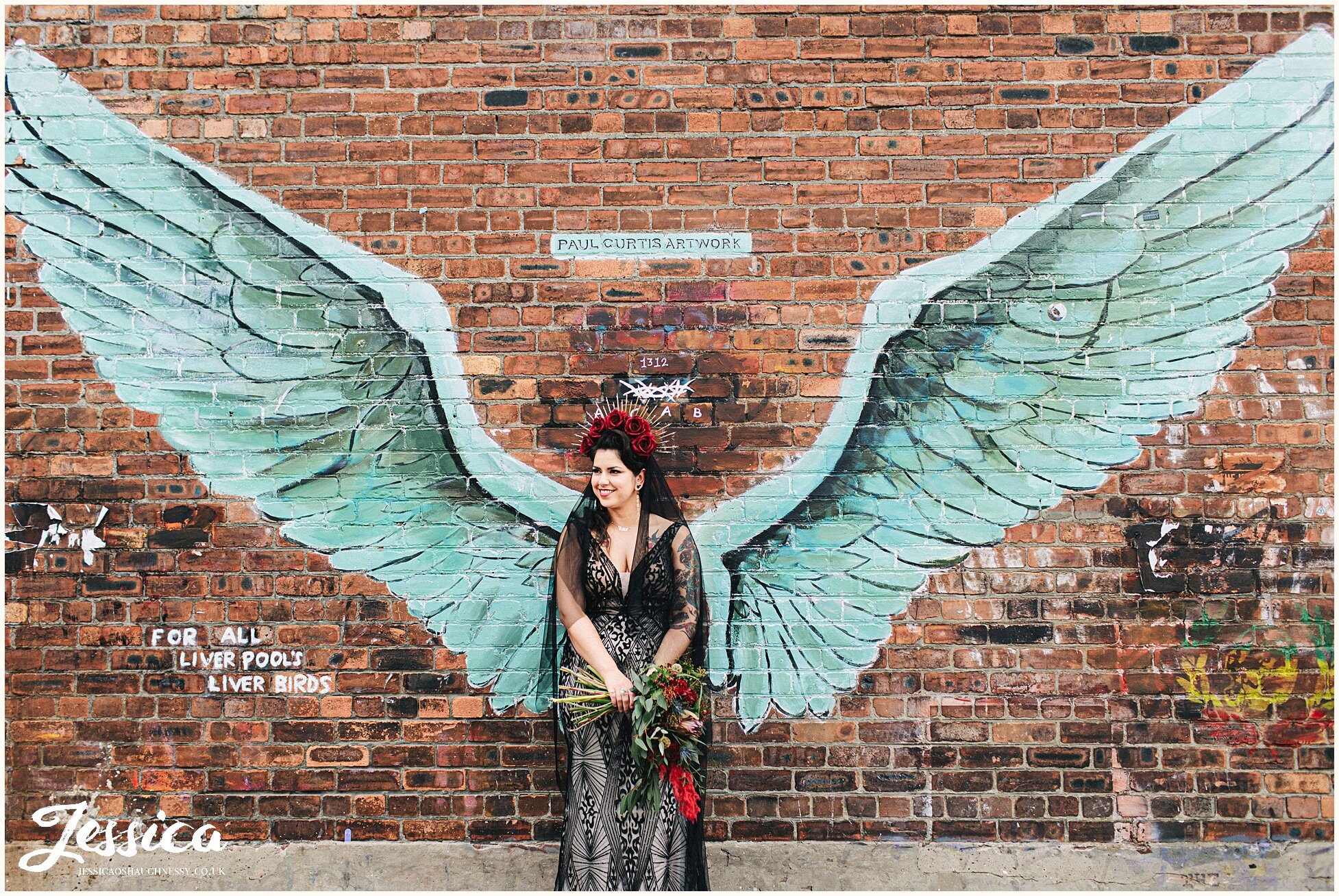 bride poses with angel wing graffiti in the baltic triange