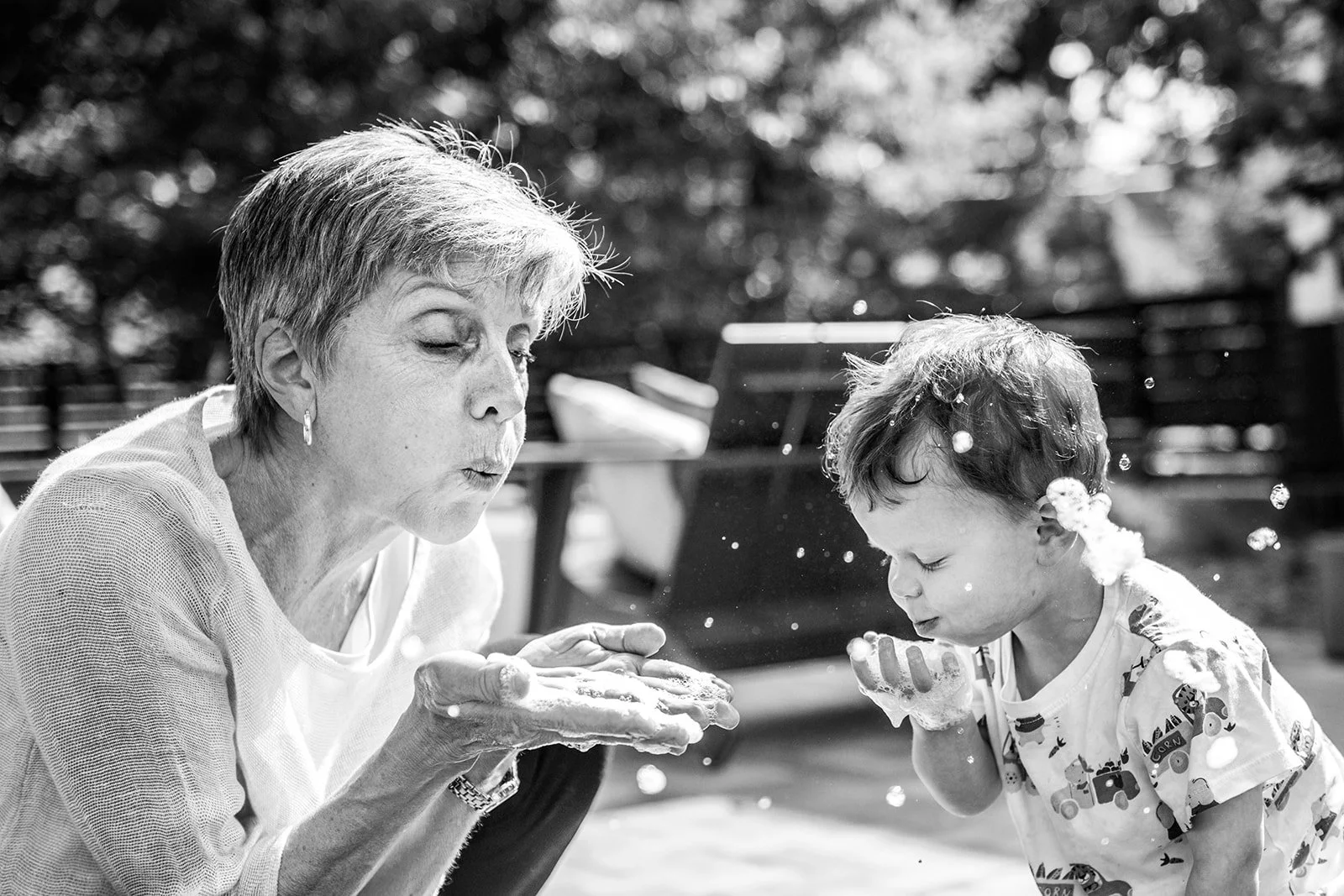 A grandmother and grandson play with bubbles during a documentary family photography session in Minneapolis, Minnesota.