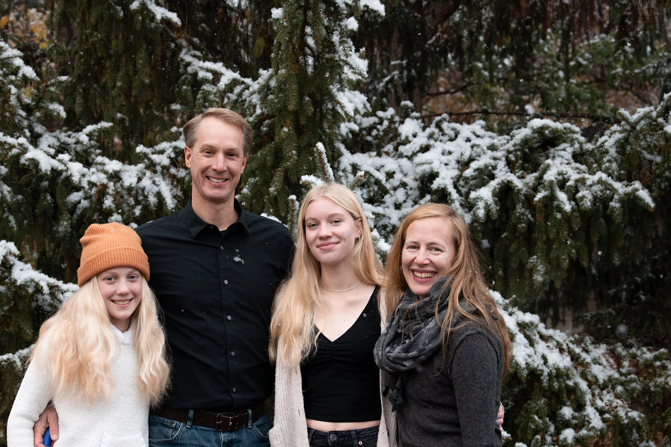 A family poses in the snow during a documentary family photography session with Shuttersmack in Minneapolis, Minnesota.