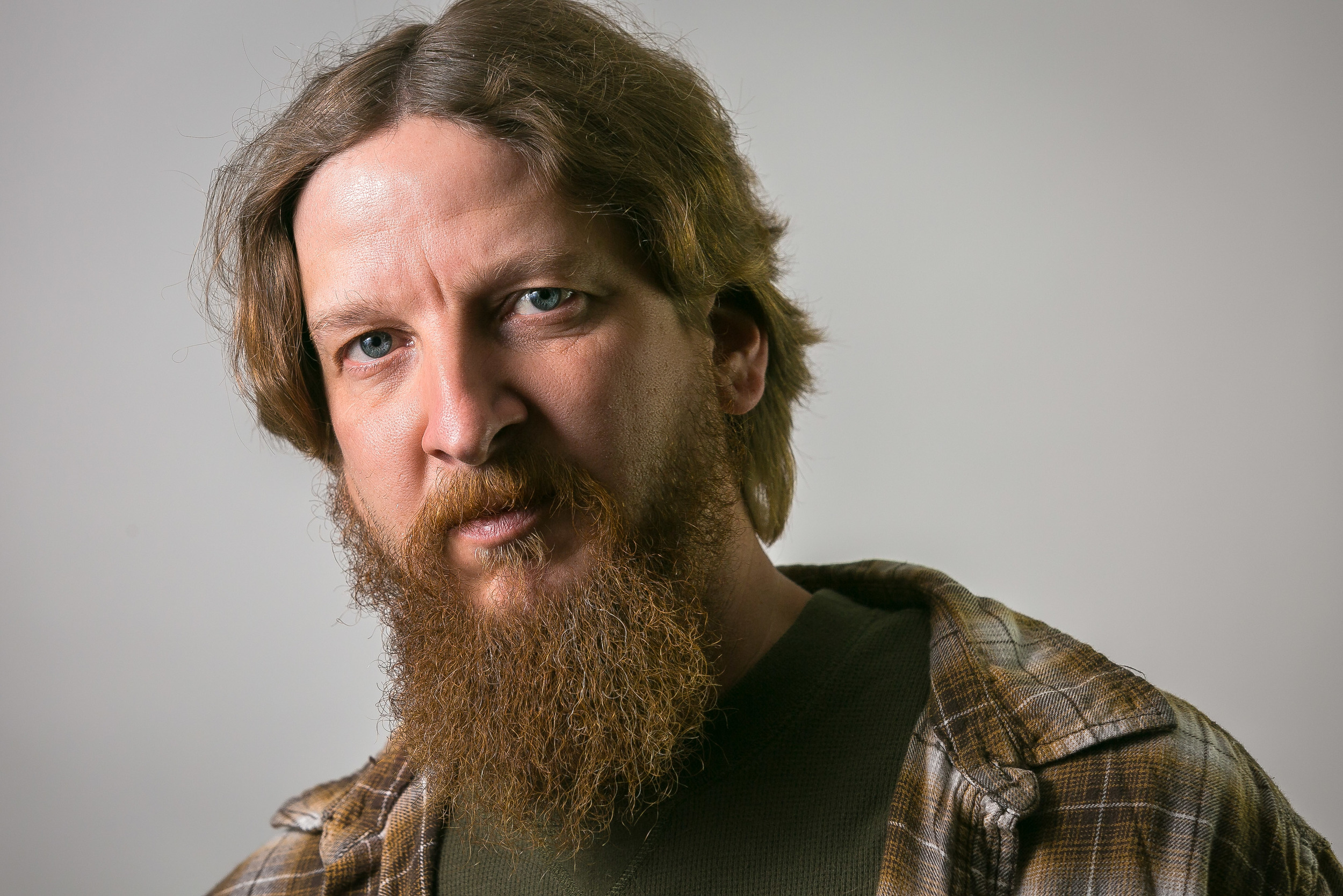 This shot was taken with a speedlite through an umbrella. The light is about 4 feet from the subject. The diffused light through the umbrella is soft and placed at an angle to get a nice Rembrandt triangle under his left eye. There is some bounce behind him that throws a little edge on the left side of his head.