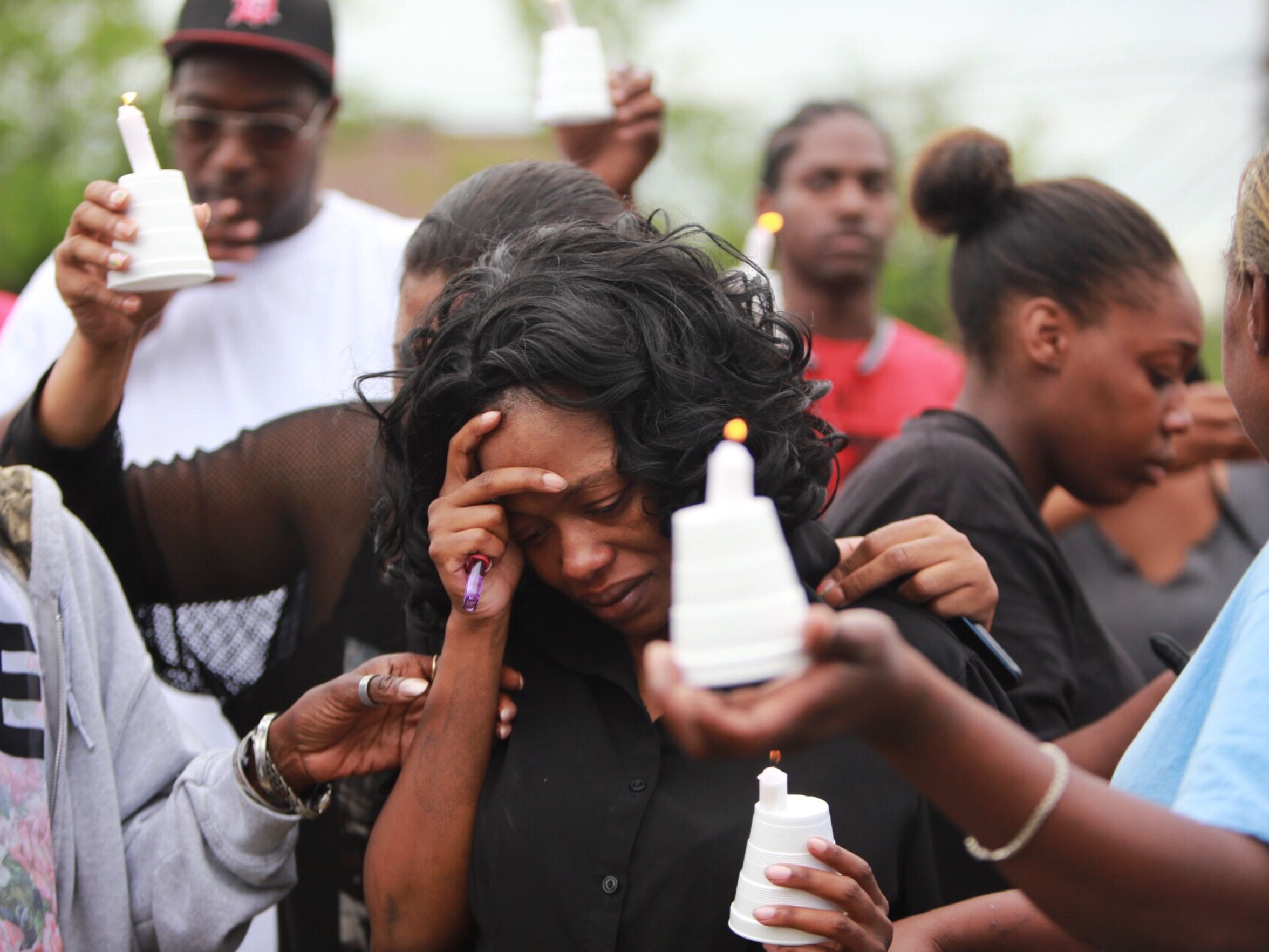 Alisha Jackson is surrounded by neighbors during a vigil held to help the families that had children killed and injured during a high speed chase in Detroit's east side on June 26.